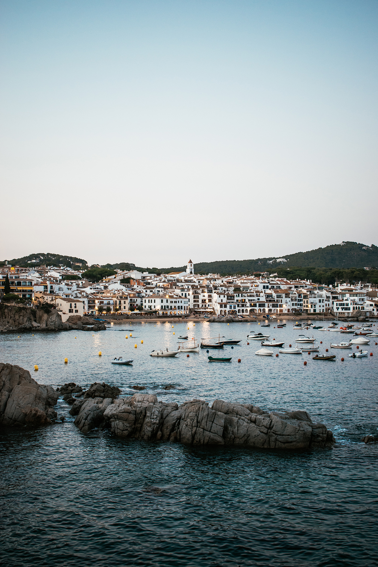 A view of a Spanish coastal town with boats anchored in the water nearby