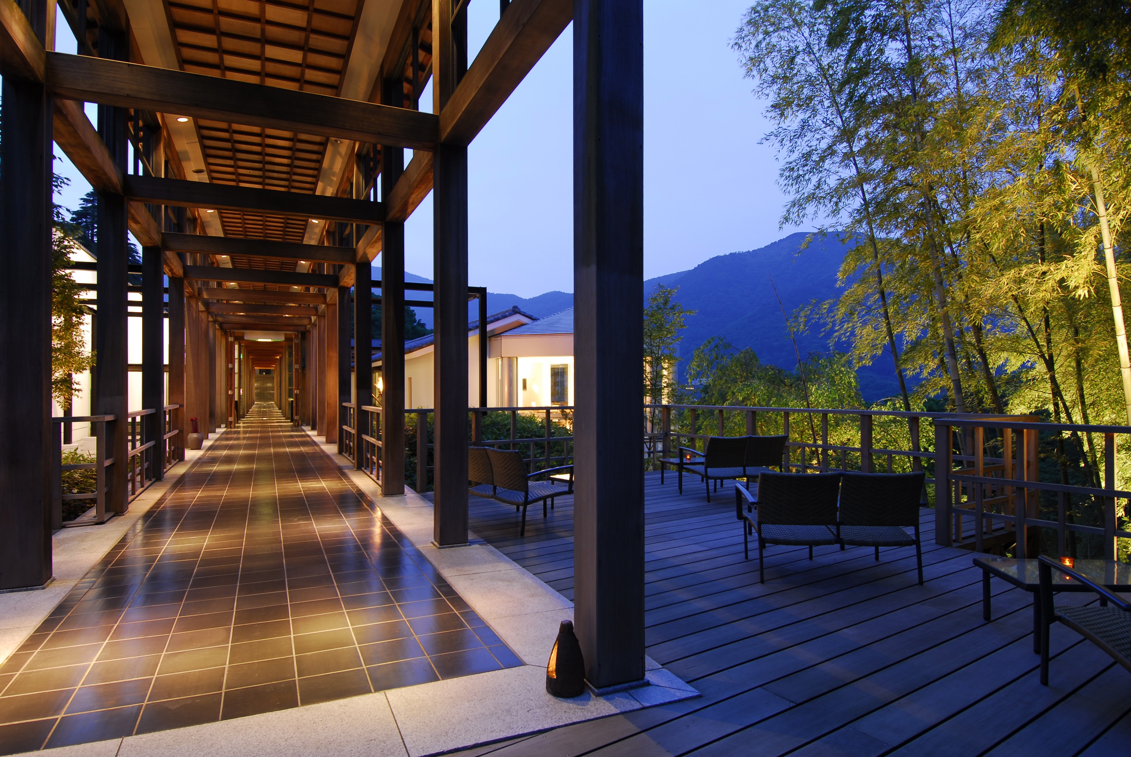 A long walkway entrance with a terrace featuring outdoor furniture, with a view of mountains in the background