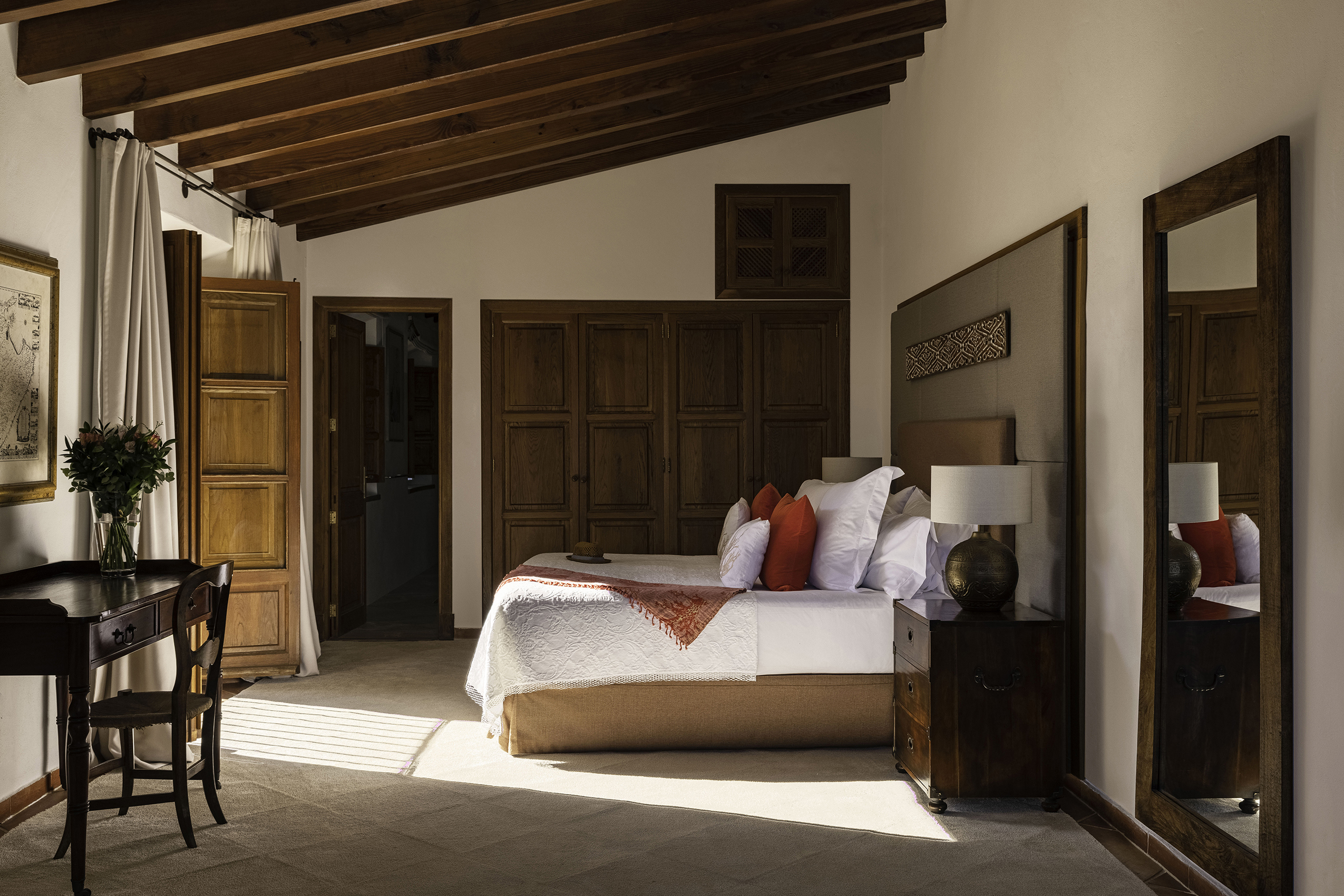 Sa Punta De S Aguila Master Suite with original beams and red and white soft furnishings