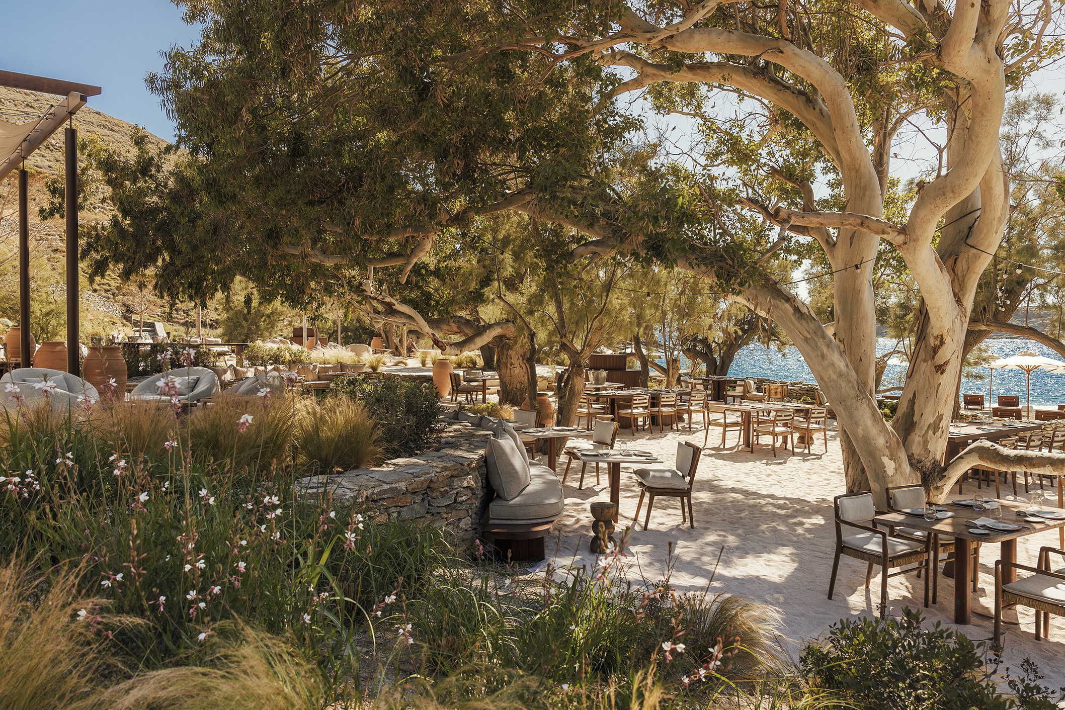 Shaded seating area of BOND beach club with well established trees and hedge borders