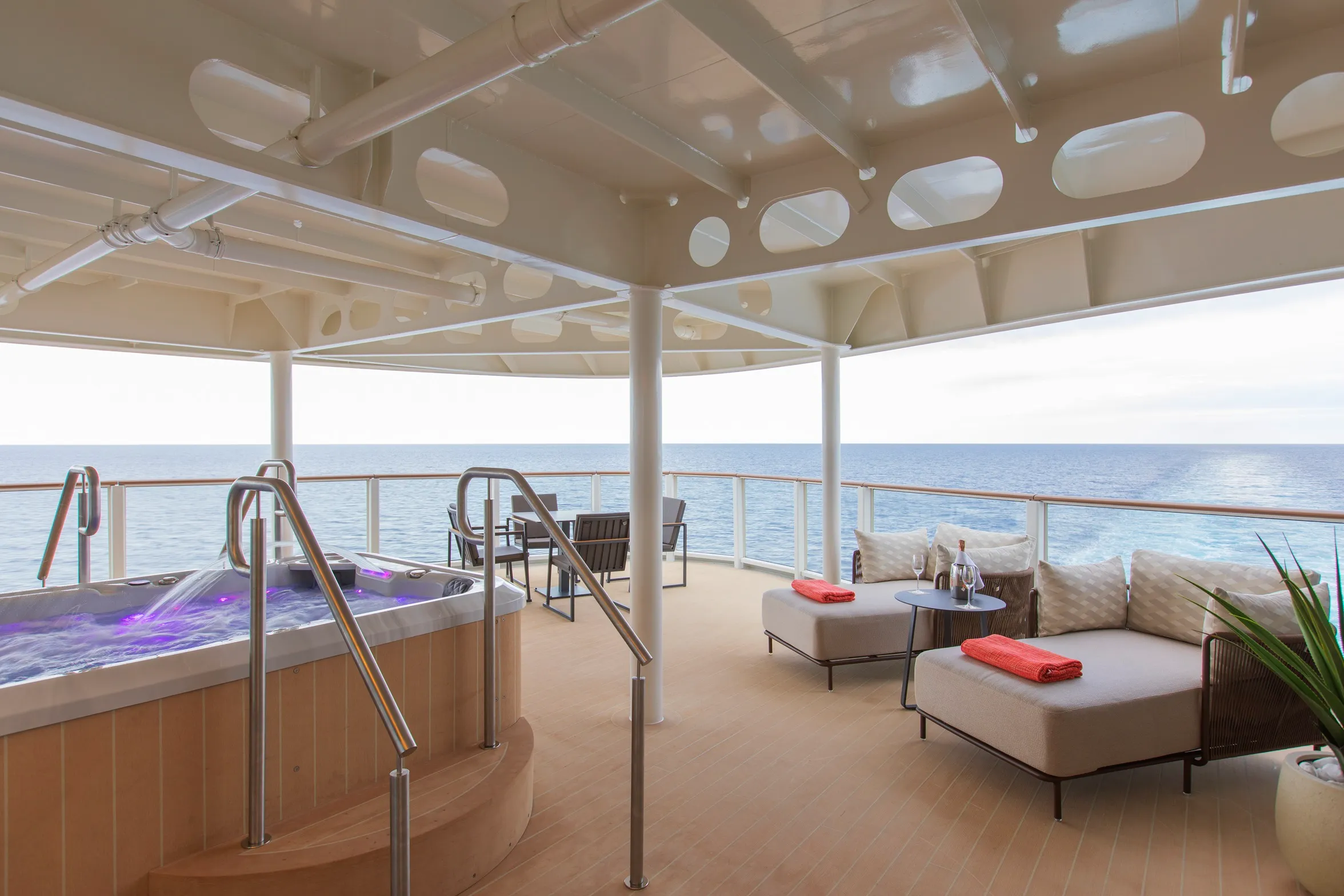 A luxurious outdoor deck with a hot tub, lounge chairs, and a stunning ocean view.