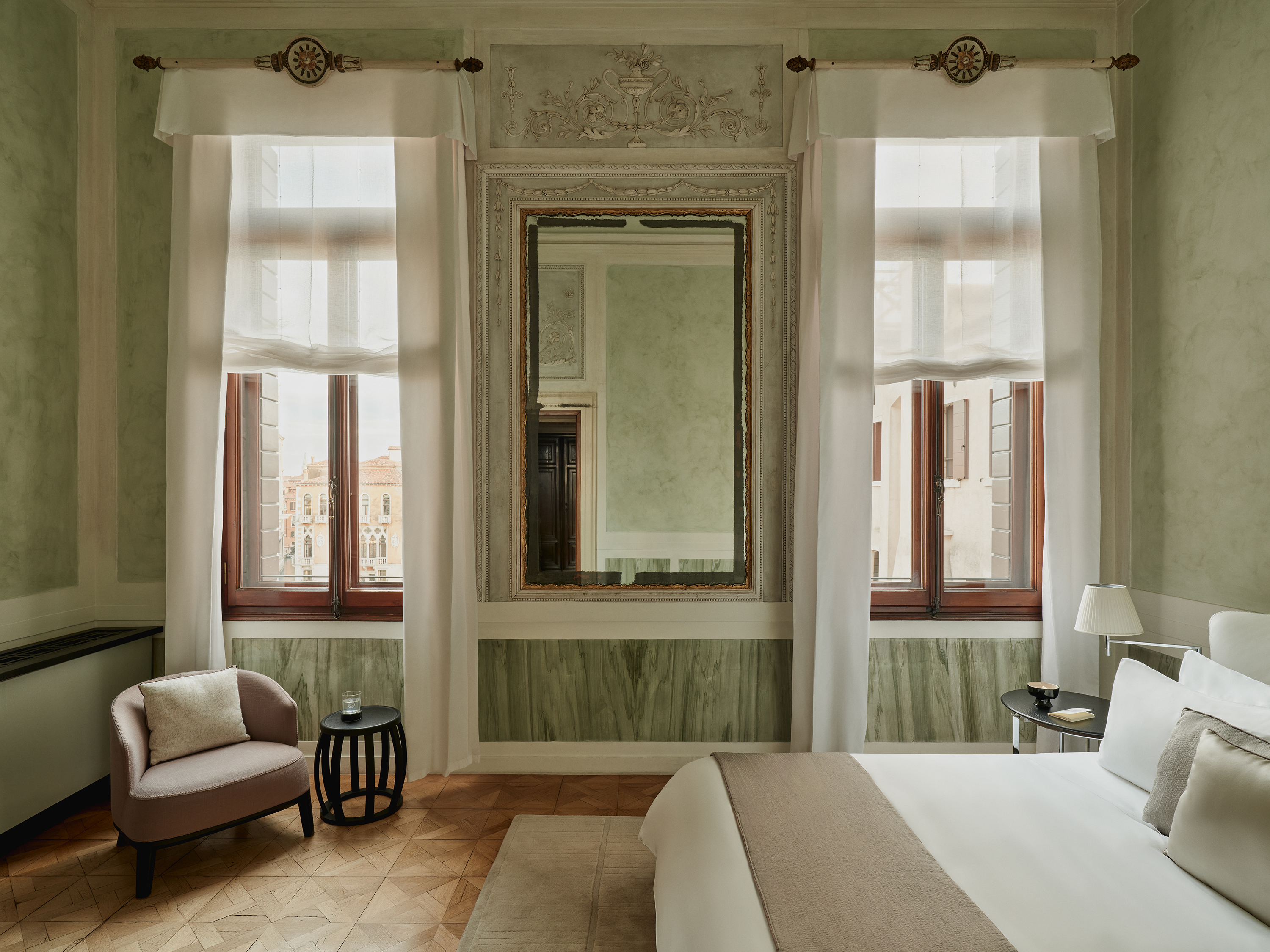 An ornate room featuring large windows and wall art with comtemporary details and furniture