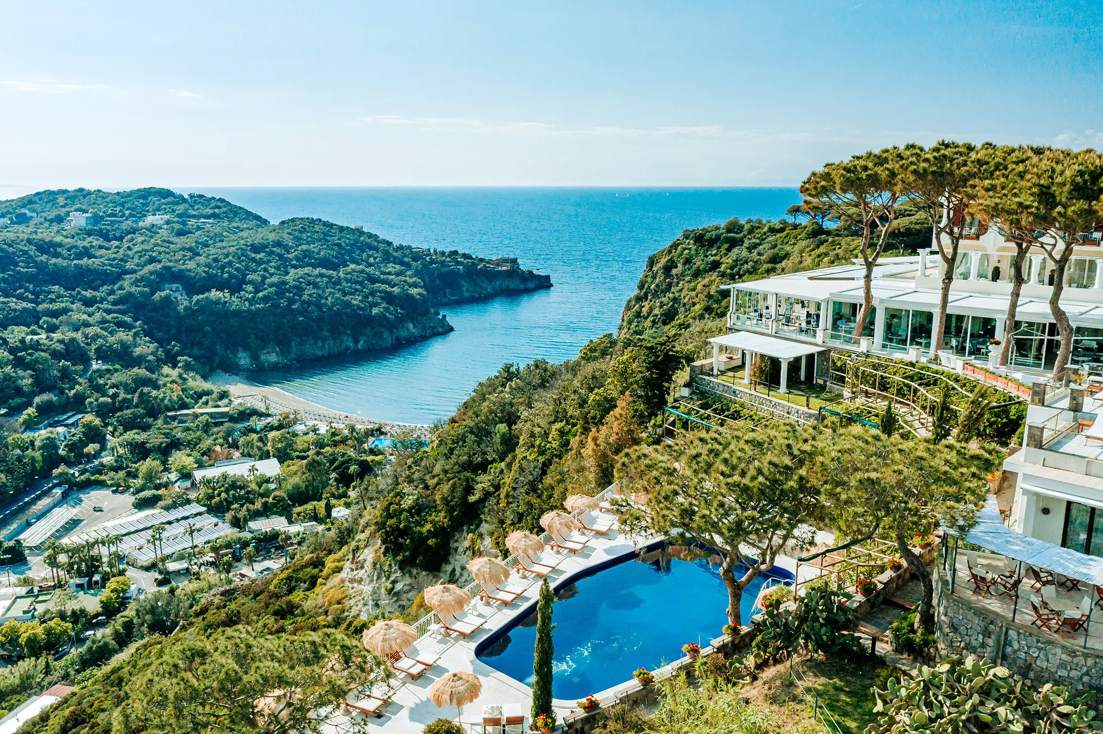 Bird's eye view of the luxurious pool area at San Montano Resort on Ischia overlooking the Mediterranean Sea and lush green hills.