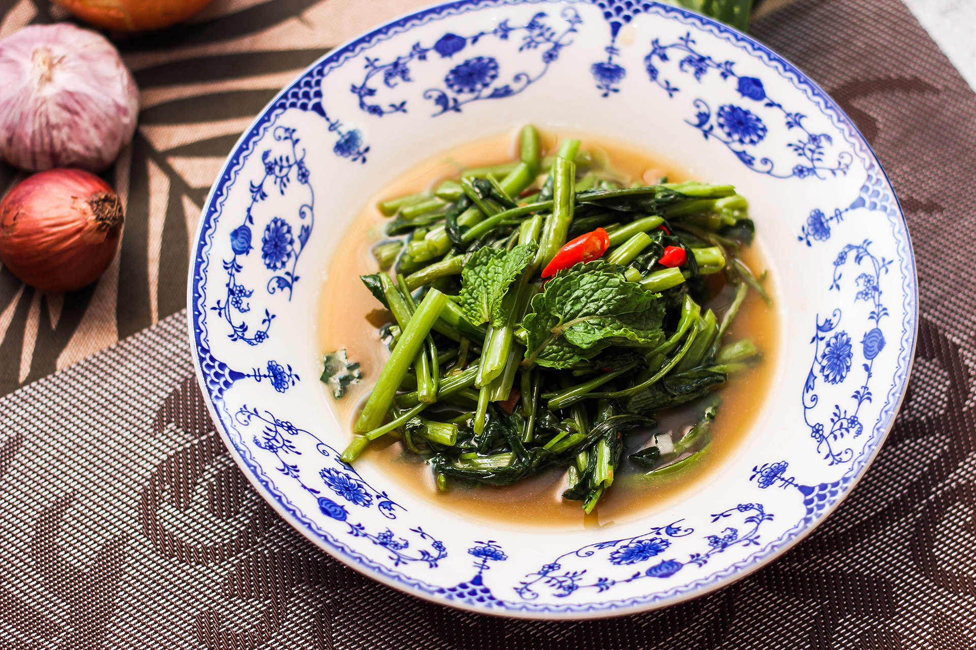 A bowl of green vegetables in a blue and white patterned bowl