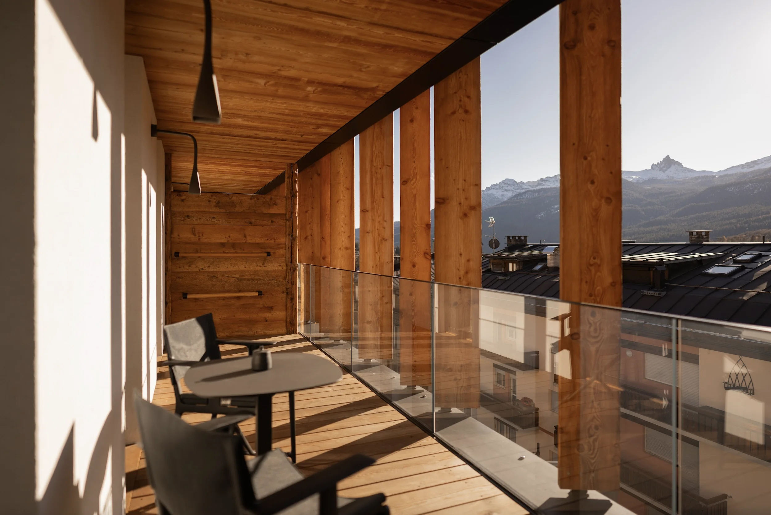 Balcony looking out over the town with minimalist furniture lit by afternoon sun