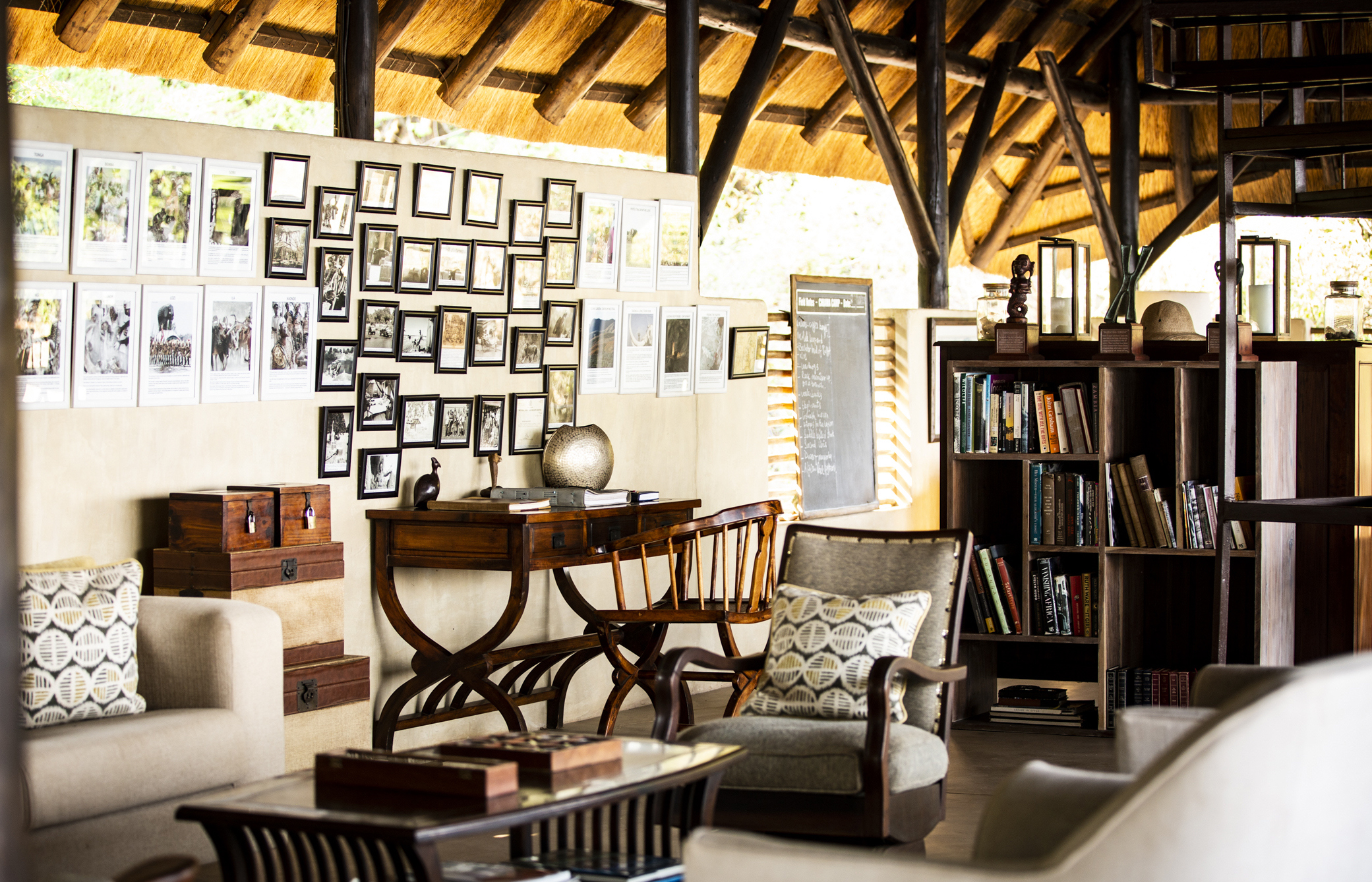 The main camp area of Chiawa Camp featuring wooden furniture and book shelves before a photo wall