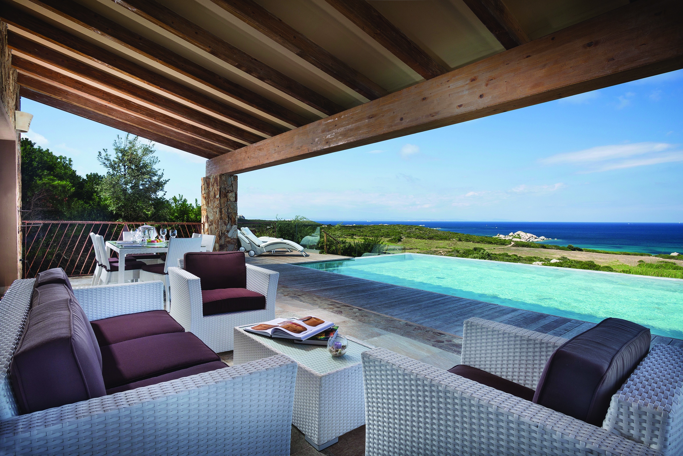 A large suite terrace featuring white rattan furniture and a private infinity pool overlooking the ocean