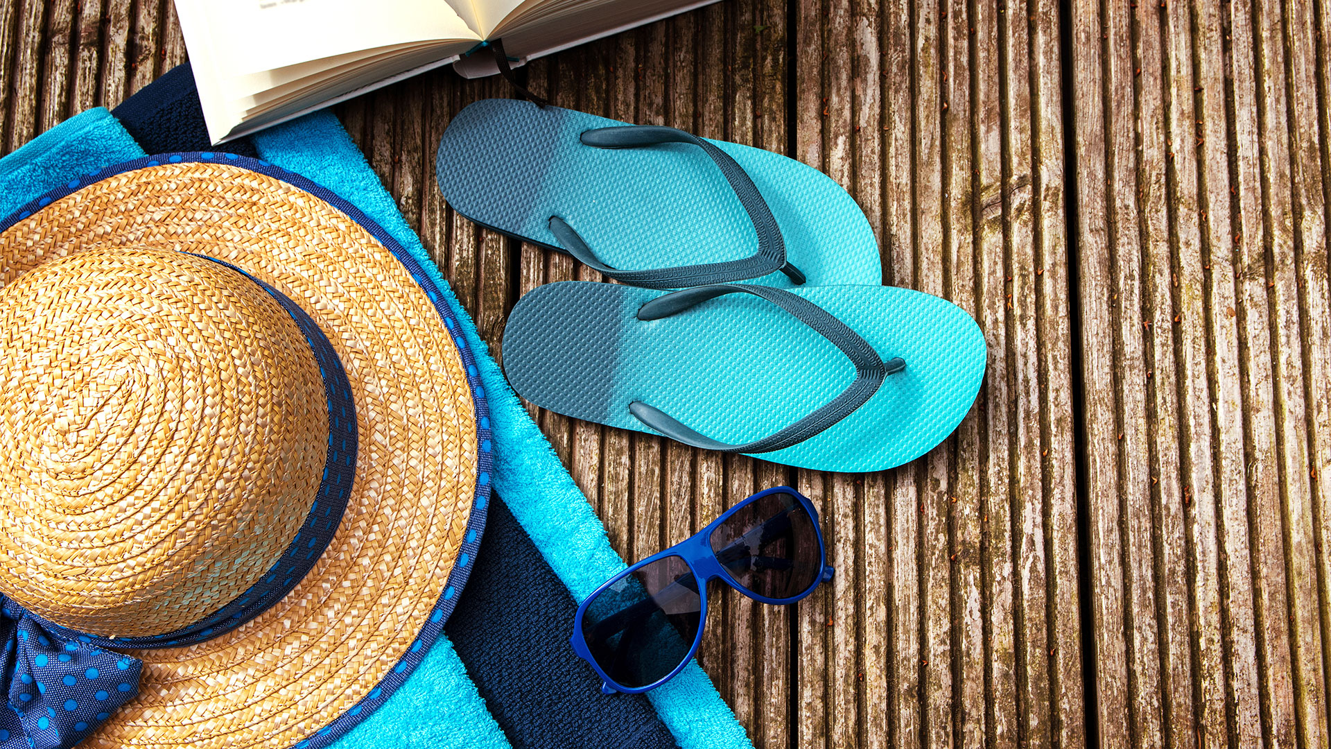 A hat, flip flops and sunglasses on a wooden deck