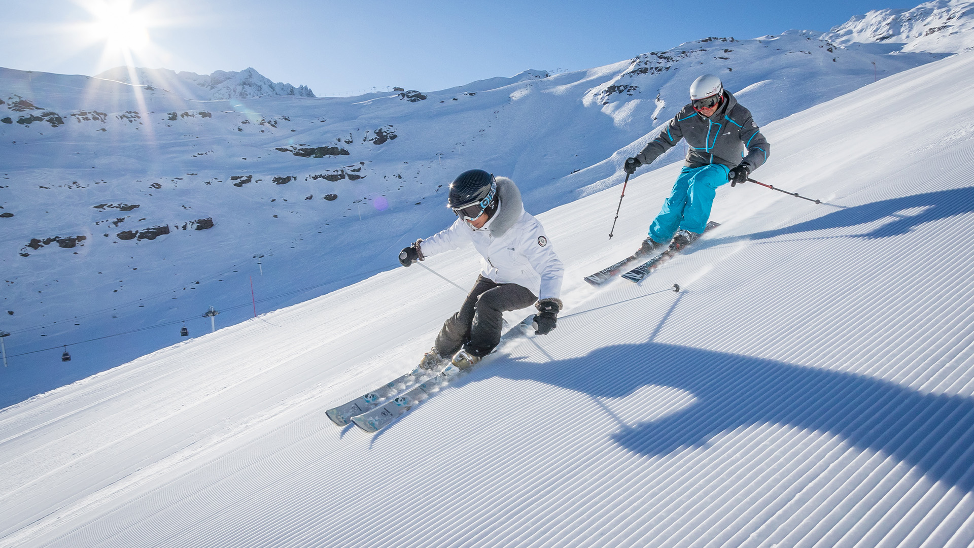 A man and woman ski on the sunny slopes of Val Thorens. France