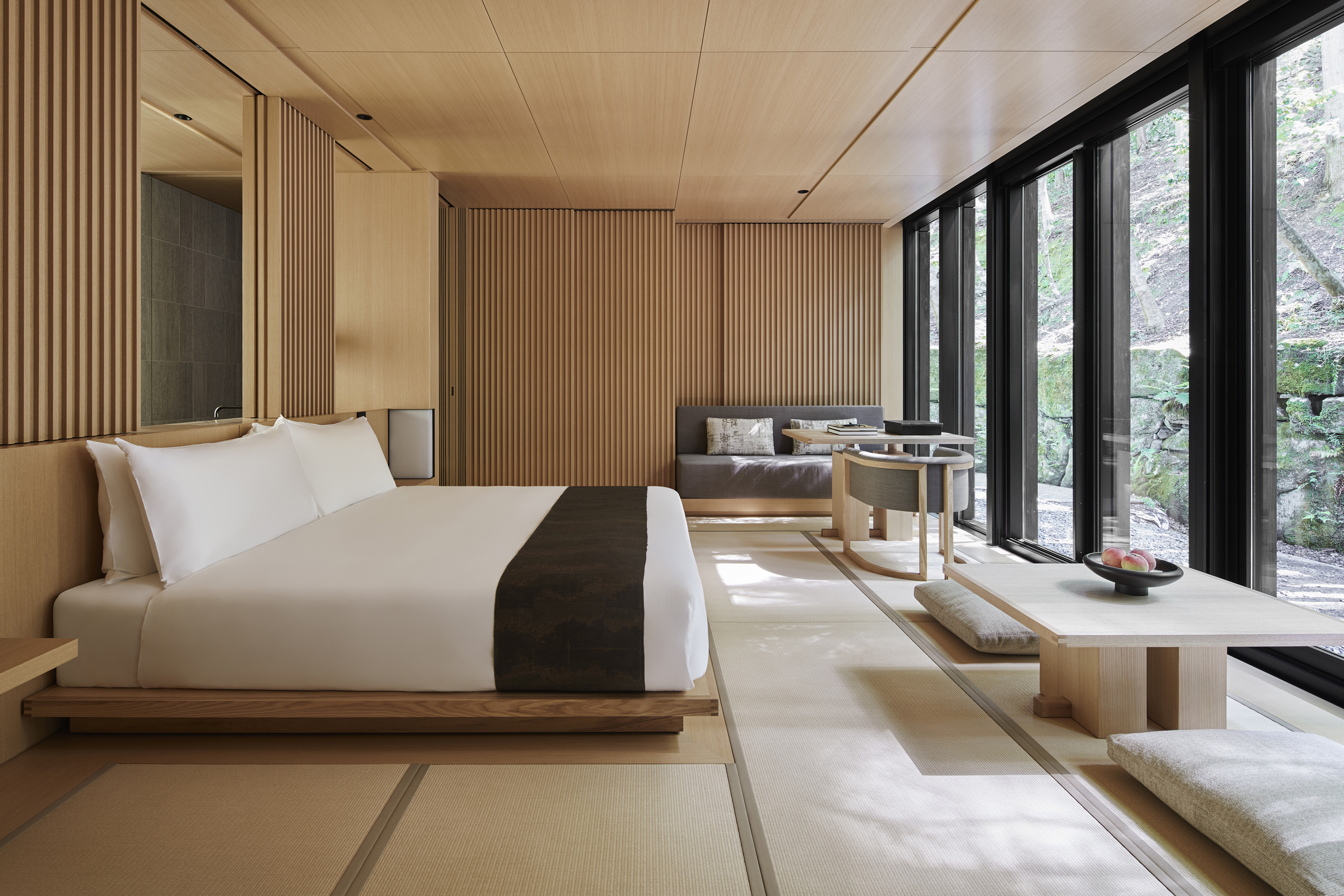 A large suite at Aman Kyoto featuring pale wood decor and a large bed facing large windows