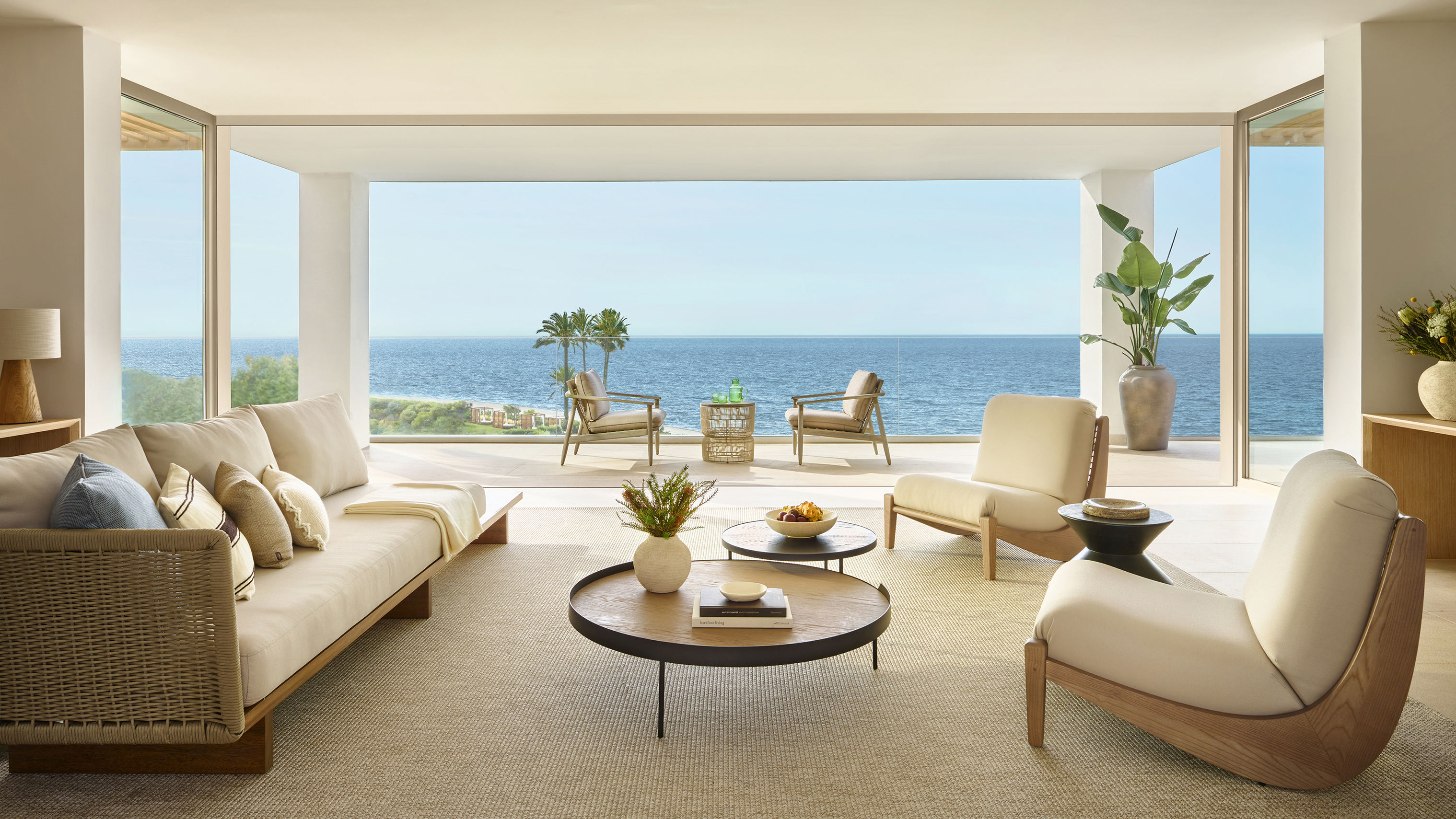 A lavish penthouse suite at Ikos Andalucia with plush furniture in neutral tones and a large balcony with ocean views