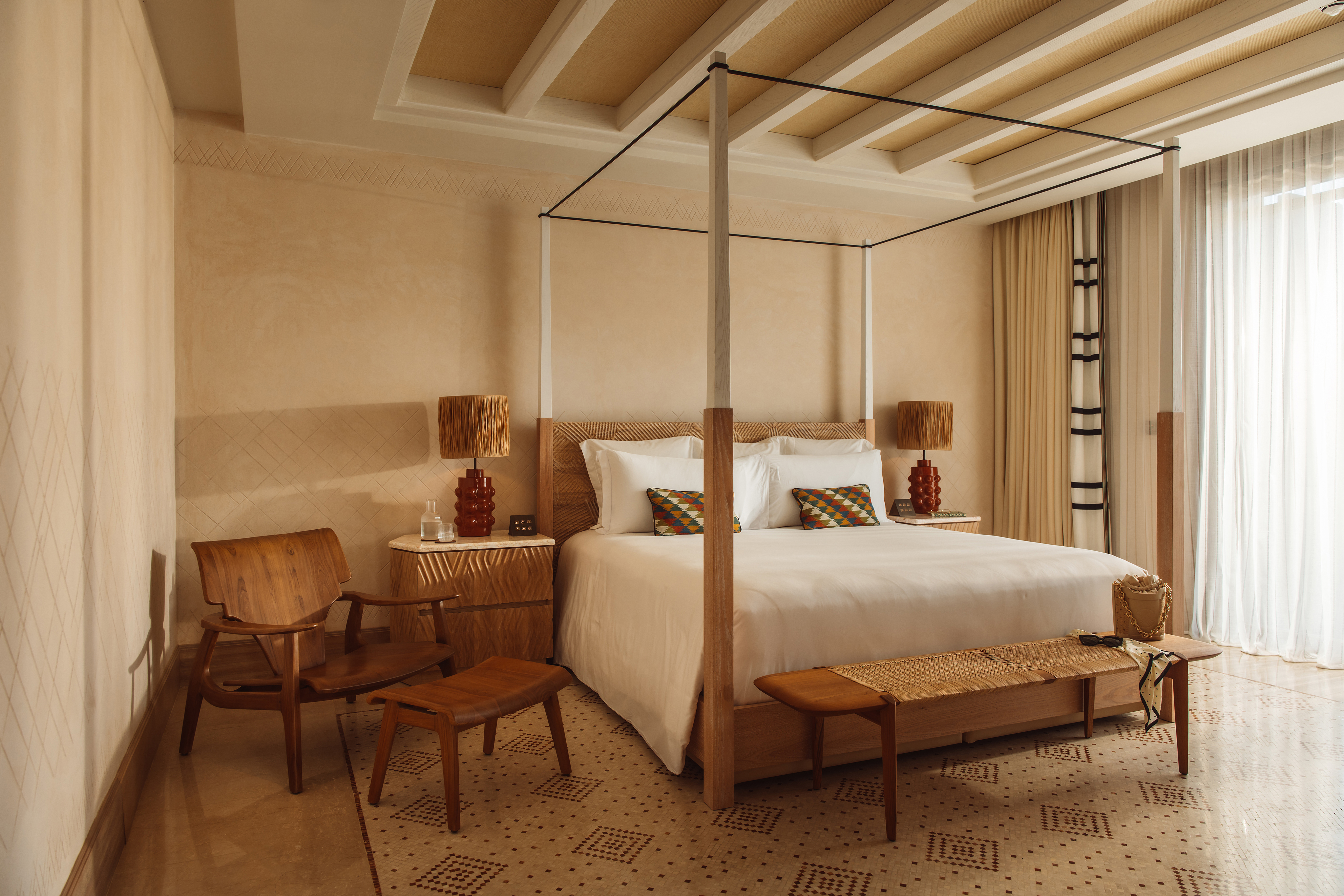 A four posted bed in the bedroom of a villa at Royal Mansour Tamuda Bay, decorated in neutral tones with Moroccan soft furnishings and wooden furniture