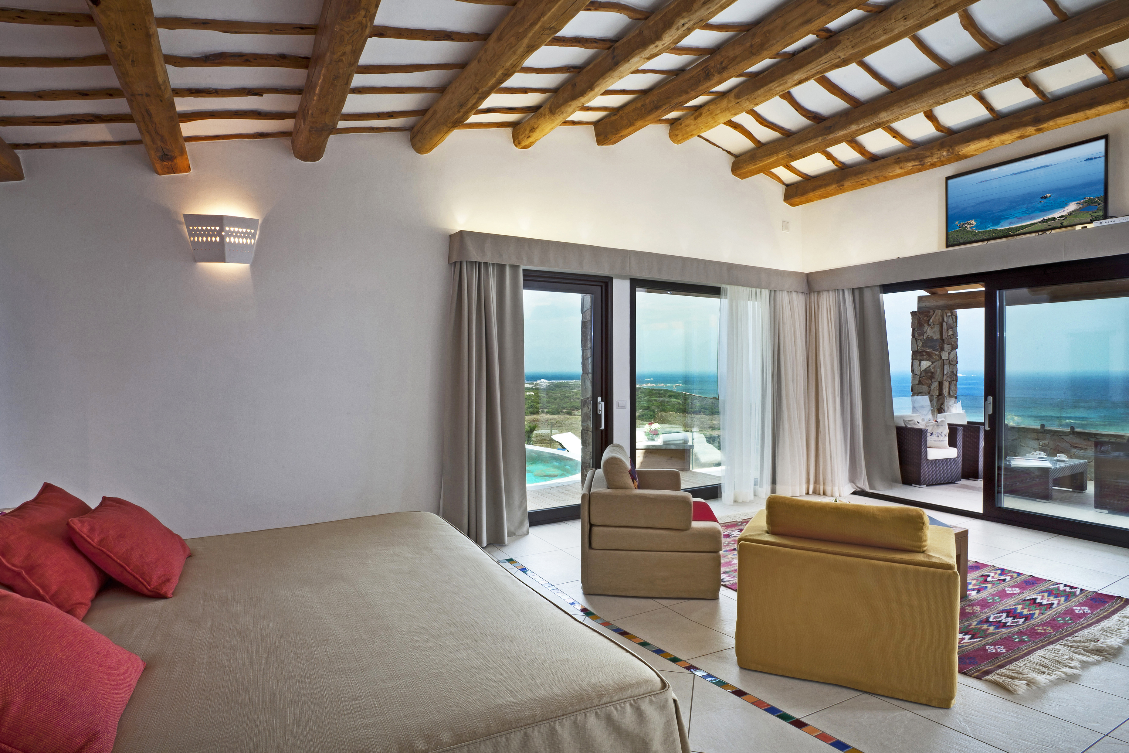 The bedroom of Imperial President Suite at La Licciola Hotel featuring beamed ceilings, comfy furniture and large windows with views of the ocean