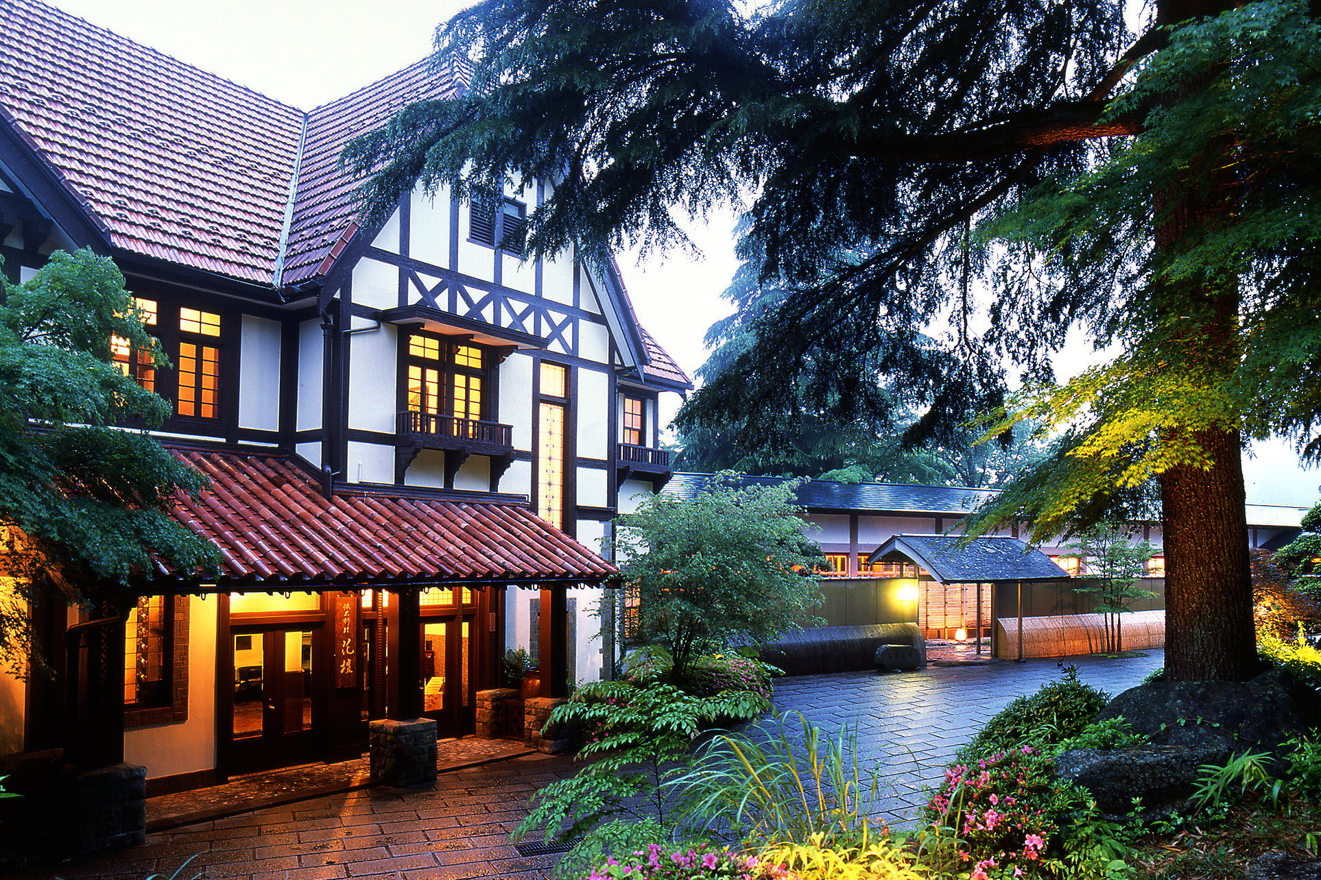 The traditional entrance of Gora Kadan with black and white walls and red tiled roofs opposite a group of trees