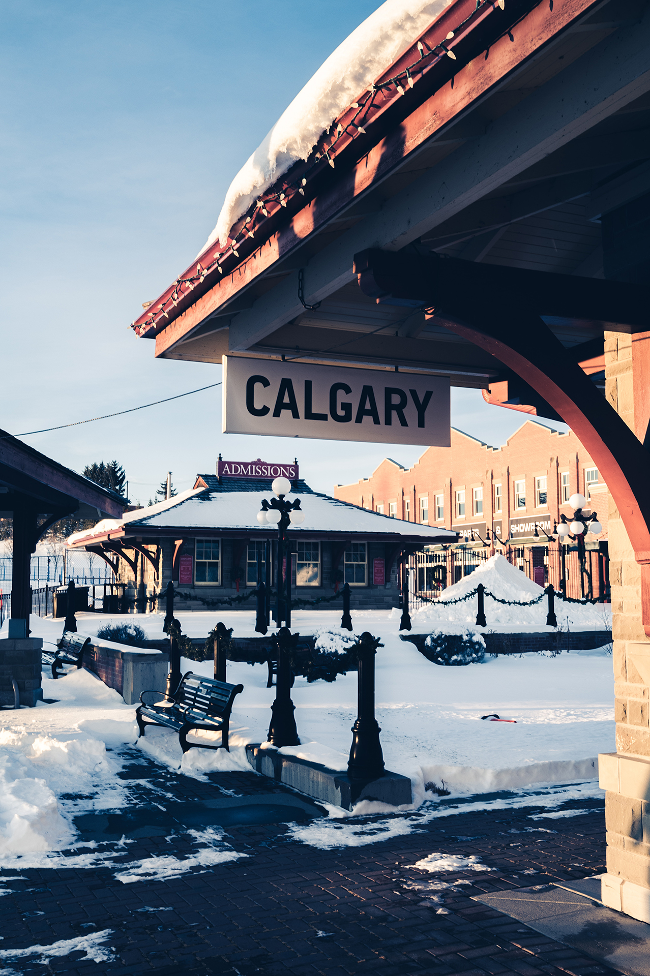 A snowy urban area with a hanging sign with the words Calgary on