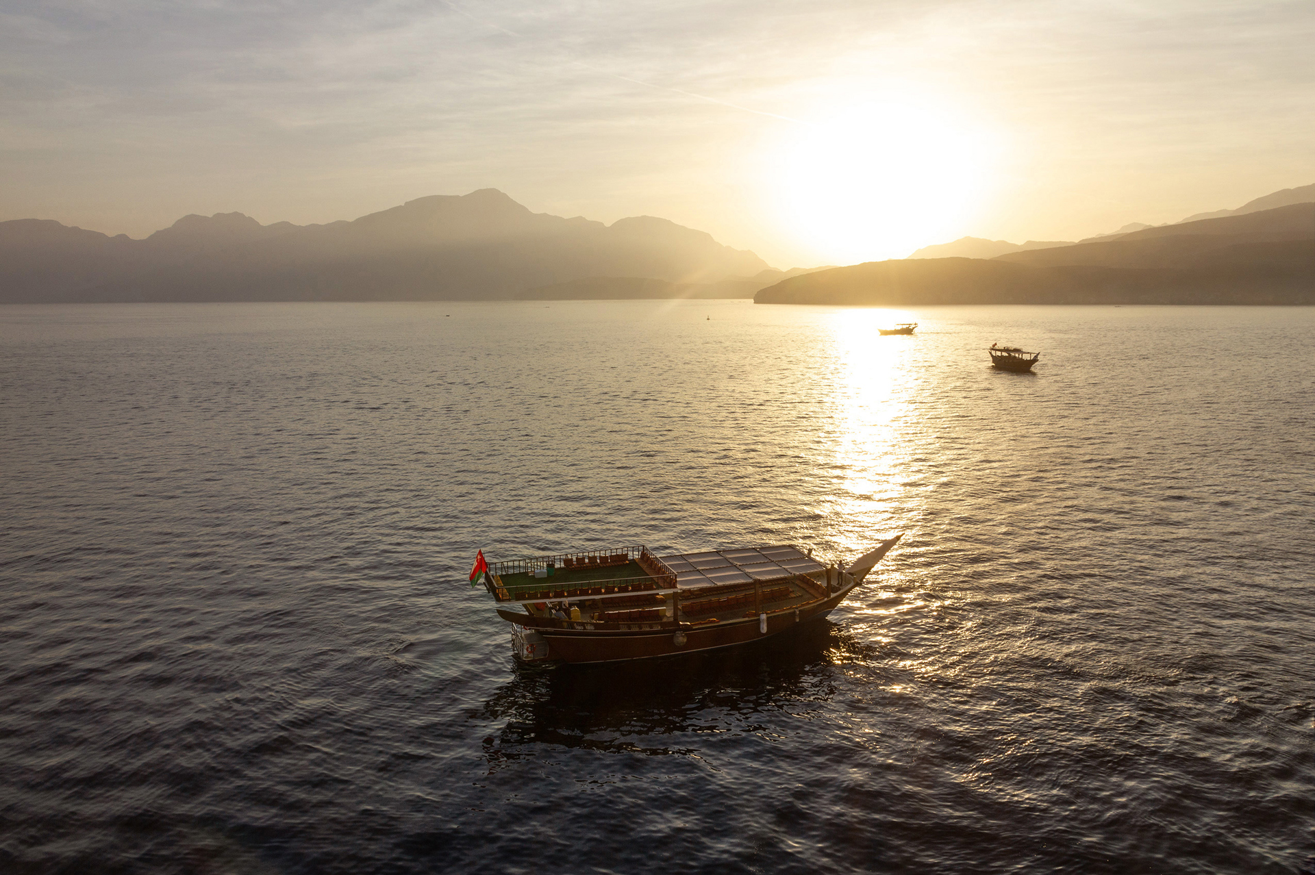 Three small boats on the water as the sun sets behind