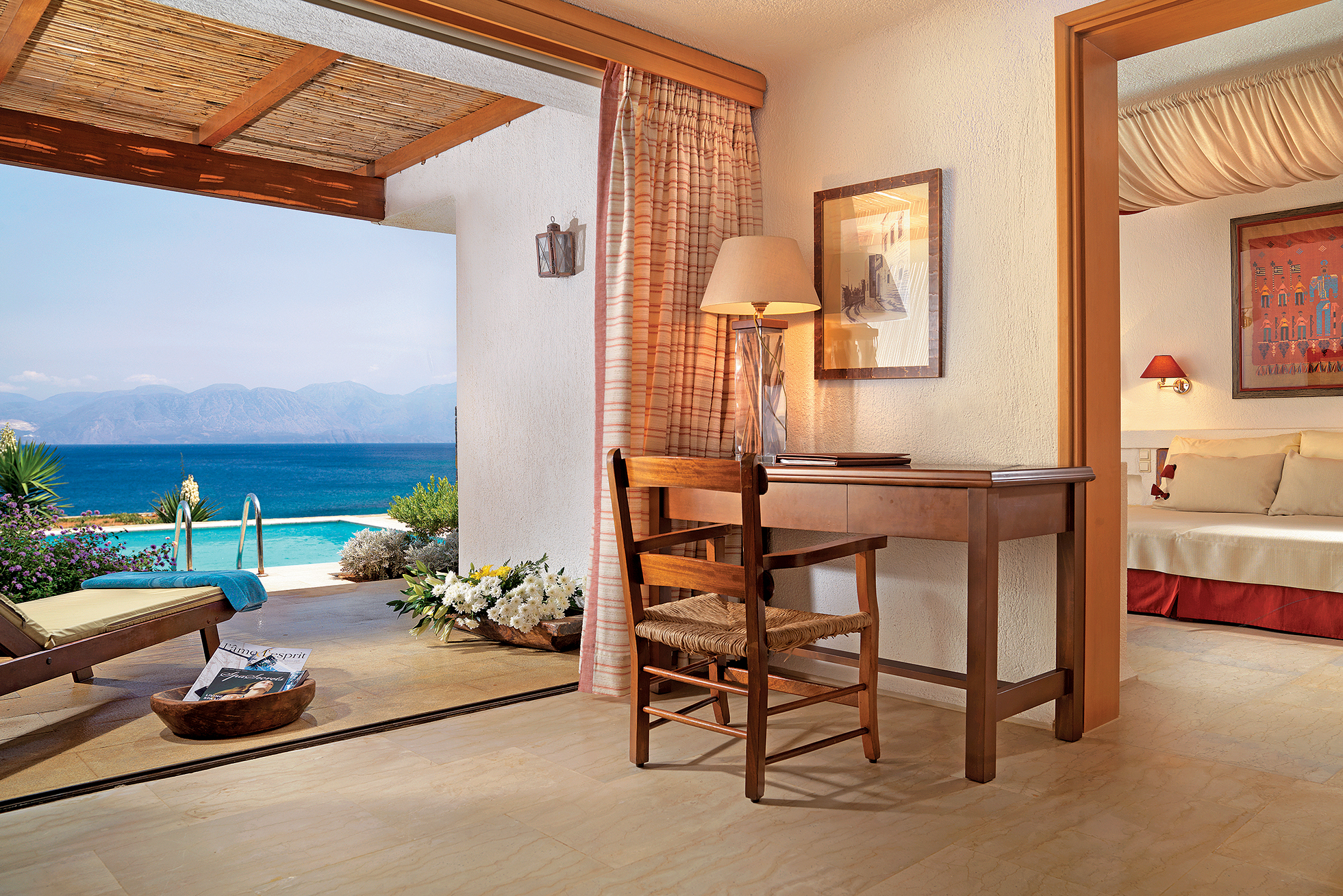 Wooden desk with lamp in a Superior Bungalow with pool outside looking out to sea