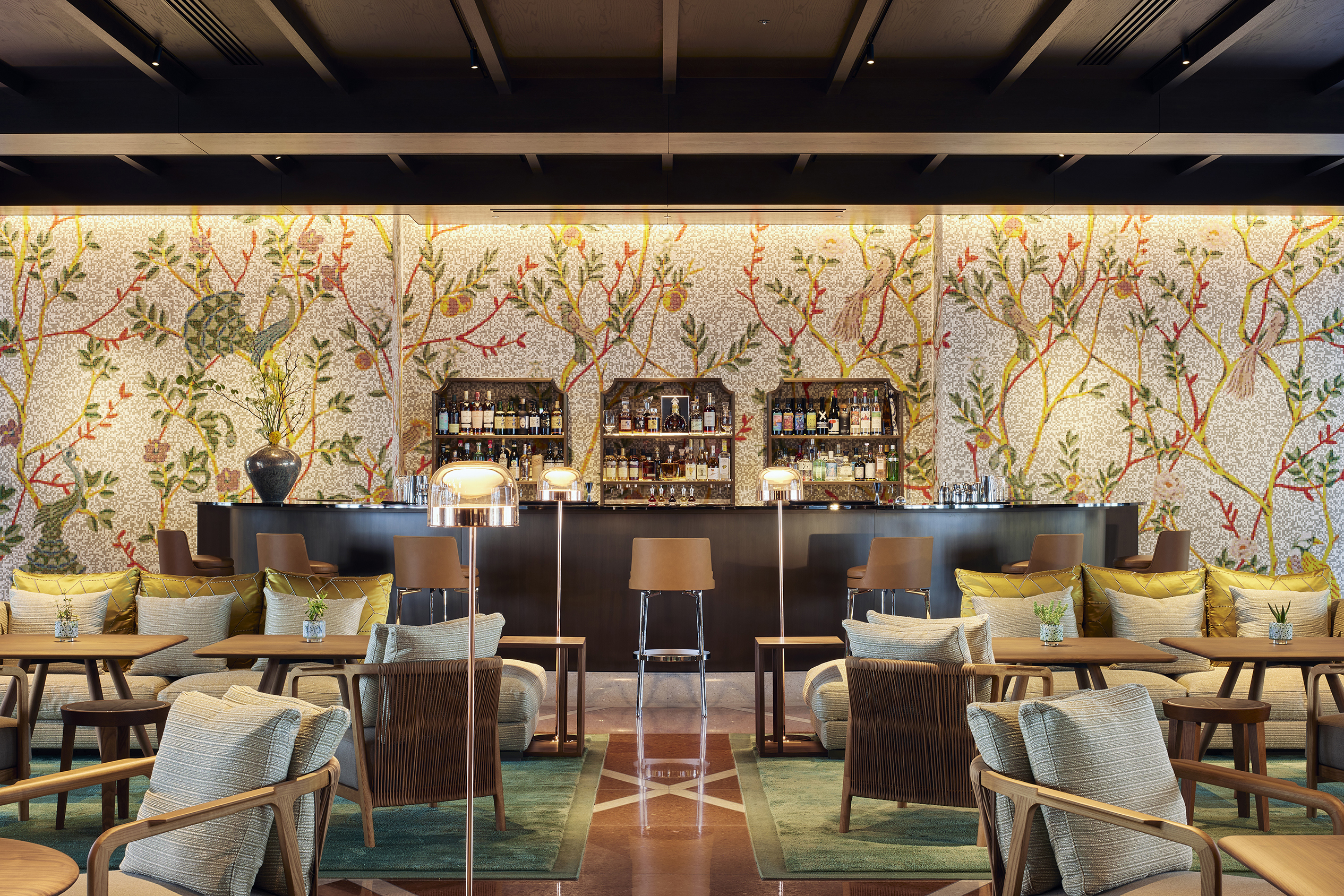 An ornate bar area with decorative wallpaper and comfy rattan seating