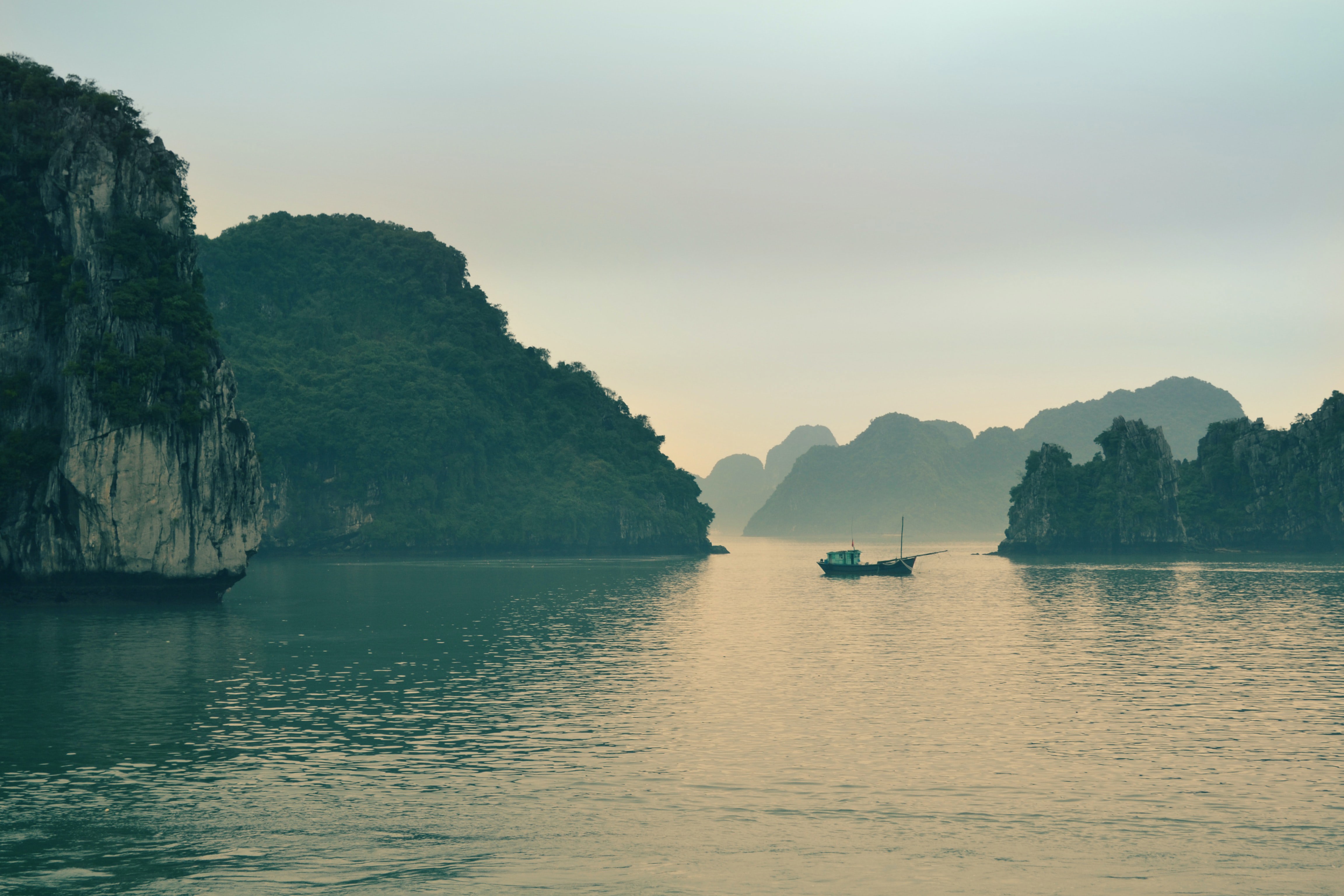 Traditional junk floating between limestone cliffs in Halong Bay