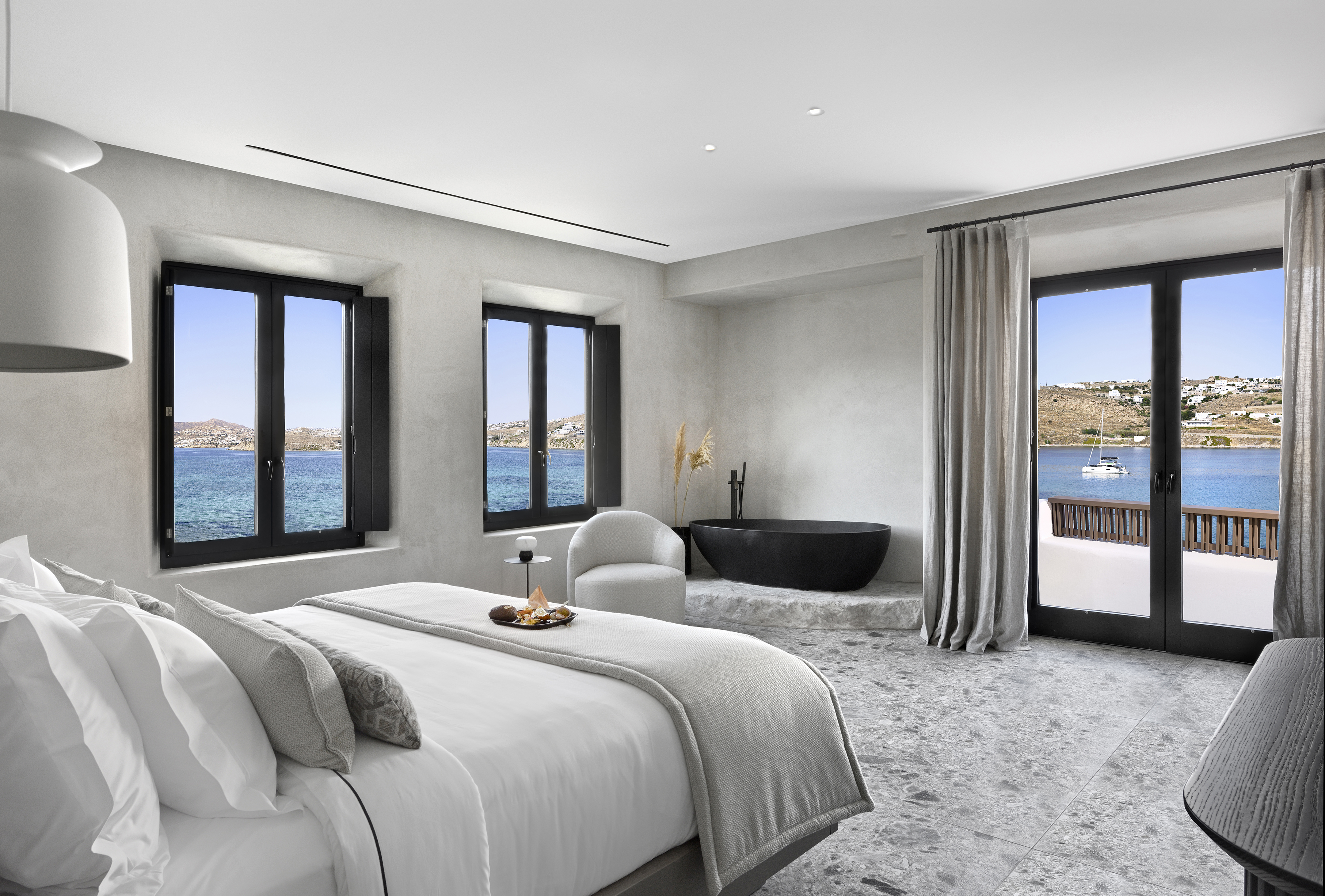 Bedroom with three windows looking out onto the bay at Aeonic Suites & Spa
