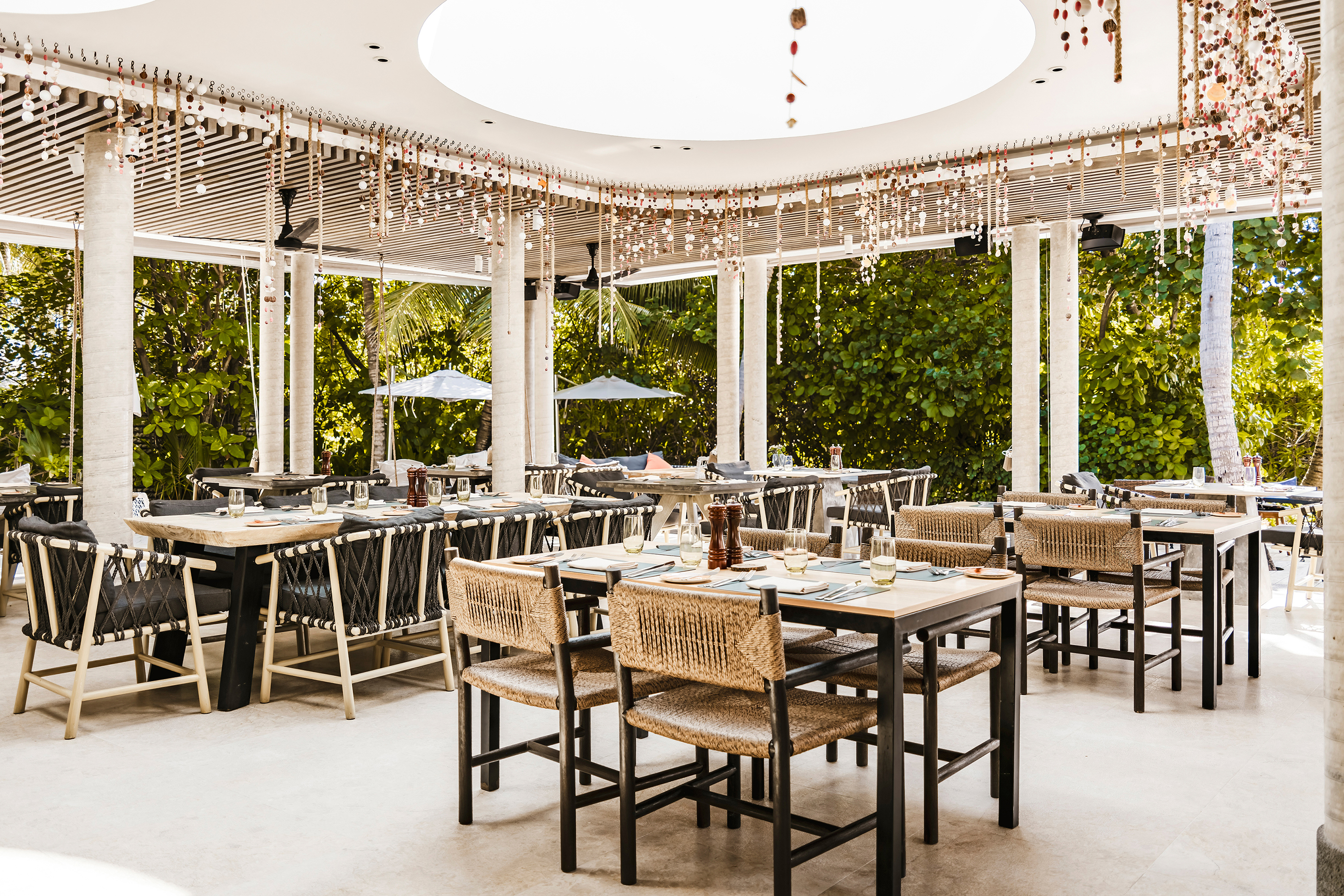 Elegant dining area at Cafe Umi at InterContinental Maldives with natural decor and lush greenery.
