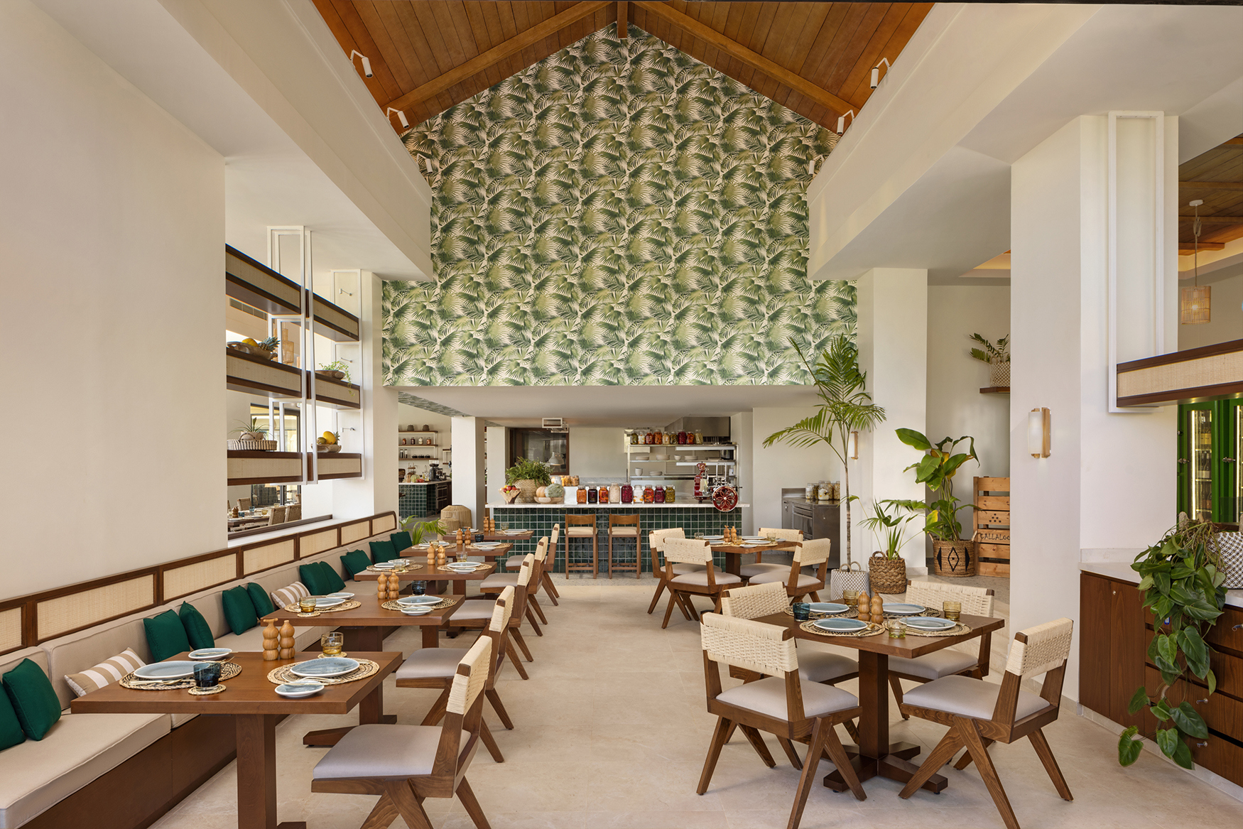 A large restaurant space filled with tasbles and chairs, the decor is light and airy with wood tones and plamts lining the walls