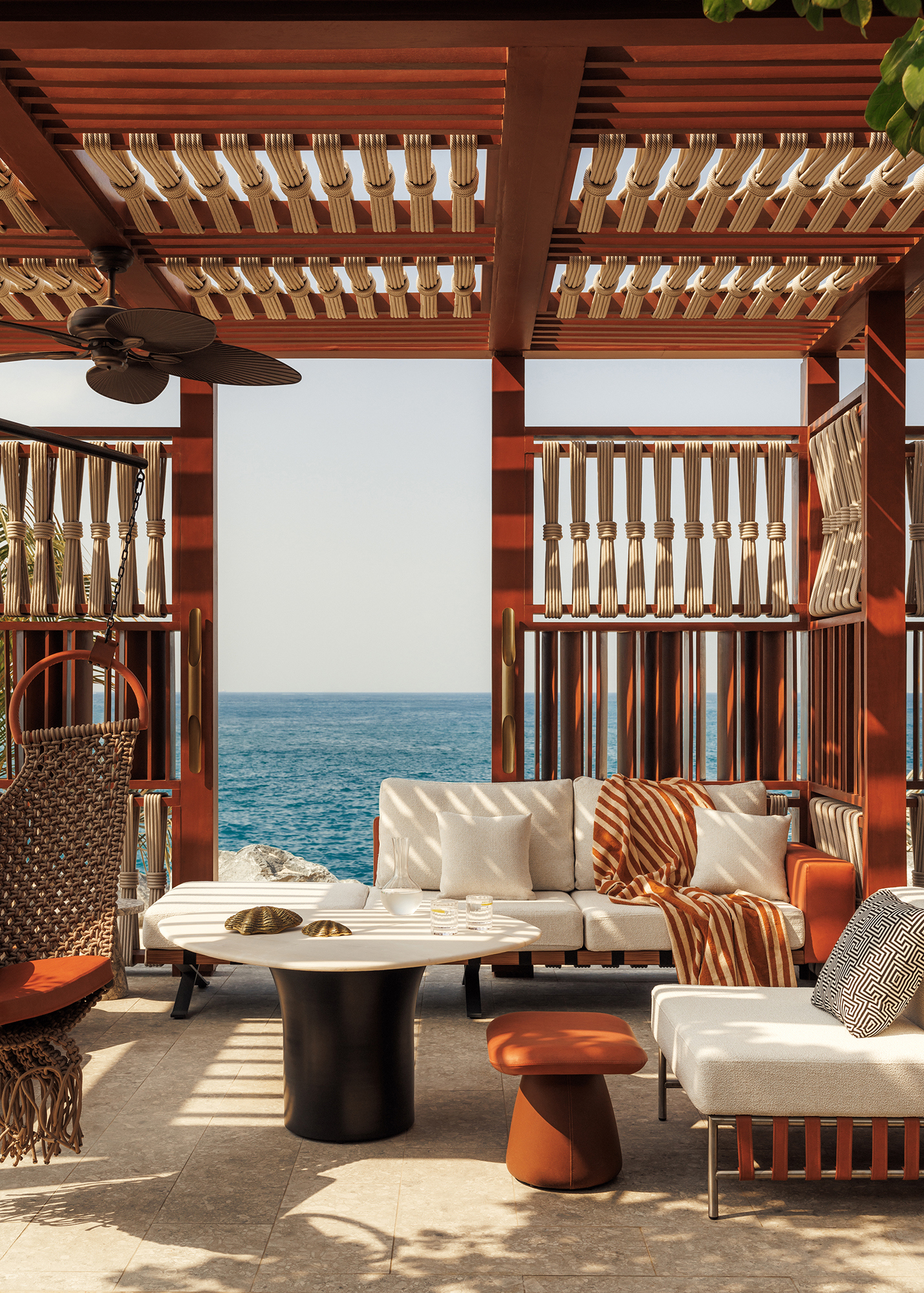 A wooden pool cabana with comfy seating and a view of the ocean