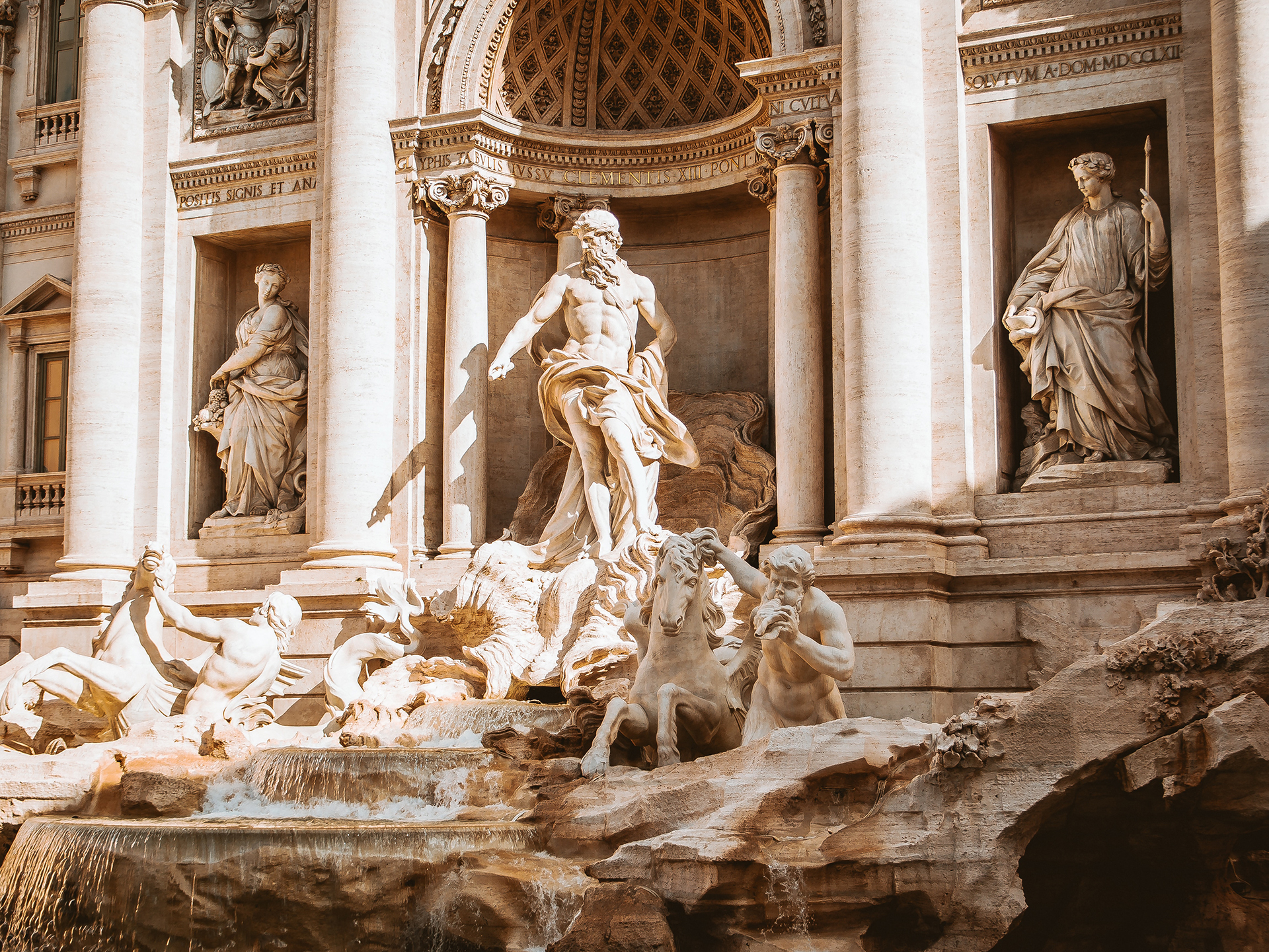 The stone statues of people and horses at the Trevi Fountain