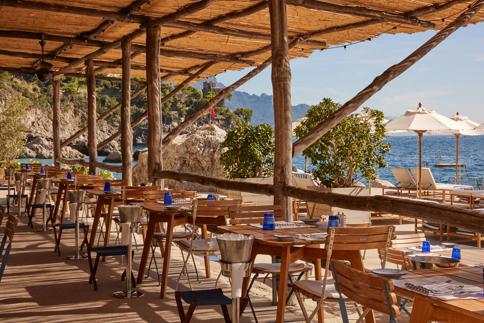 Beach Club Restaurant at Borgo Santandrea in Amalfi featuring rustic pergola-shaded dining, wooden furnishings, and stunning Mediterranean Sea views.