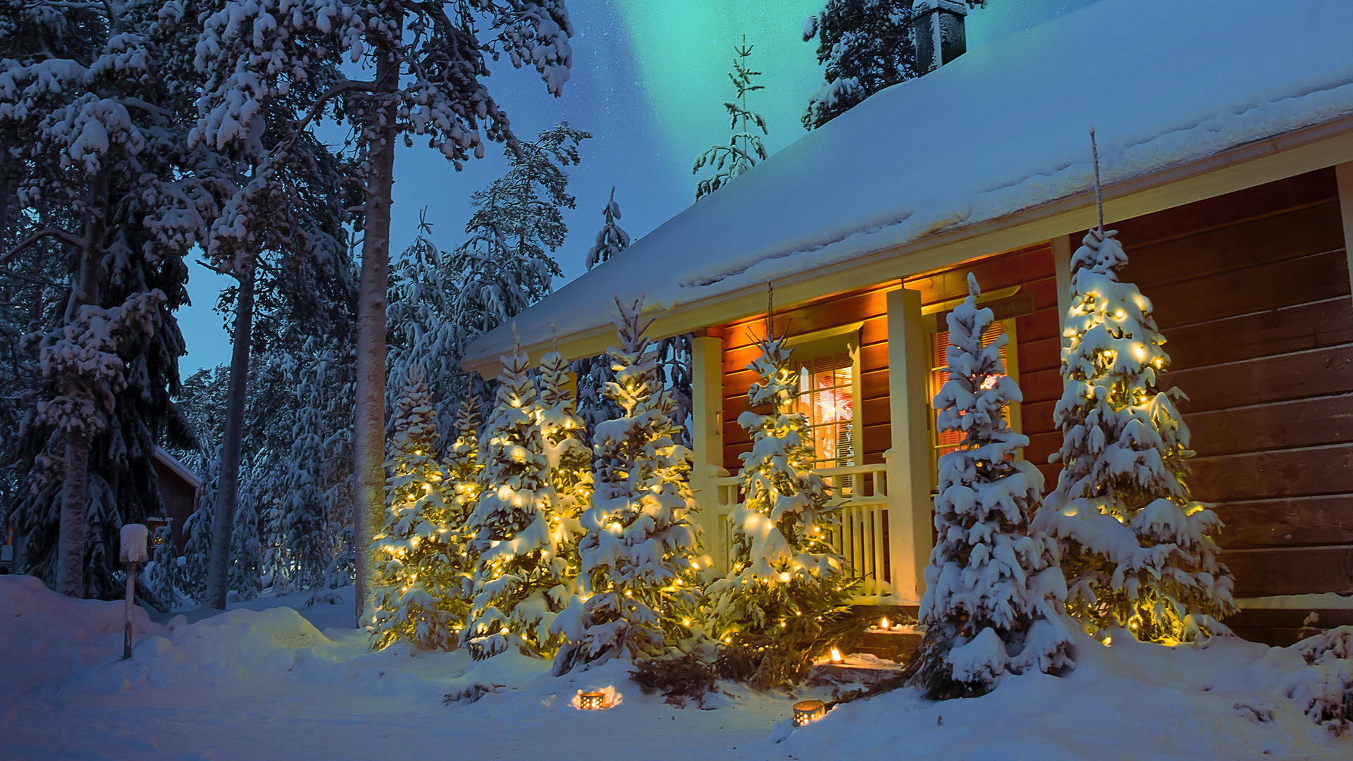 A wooden chalet lit up at night covered in snow
