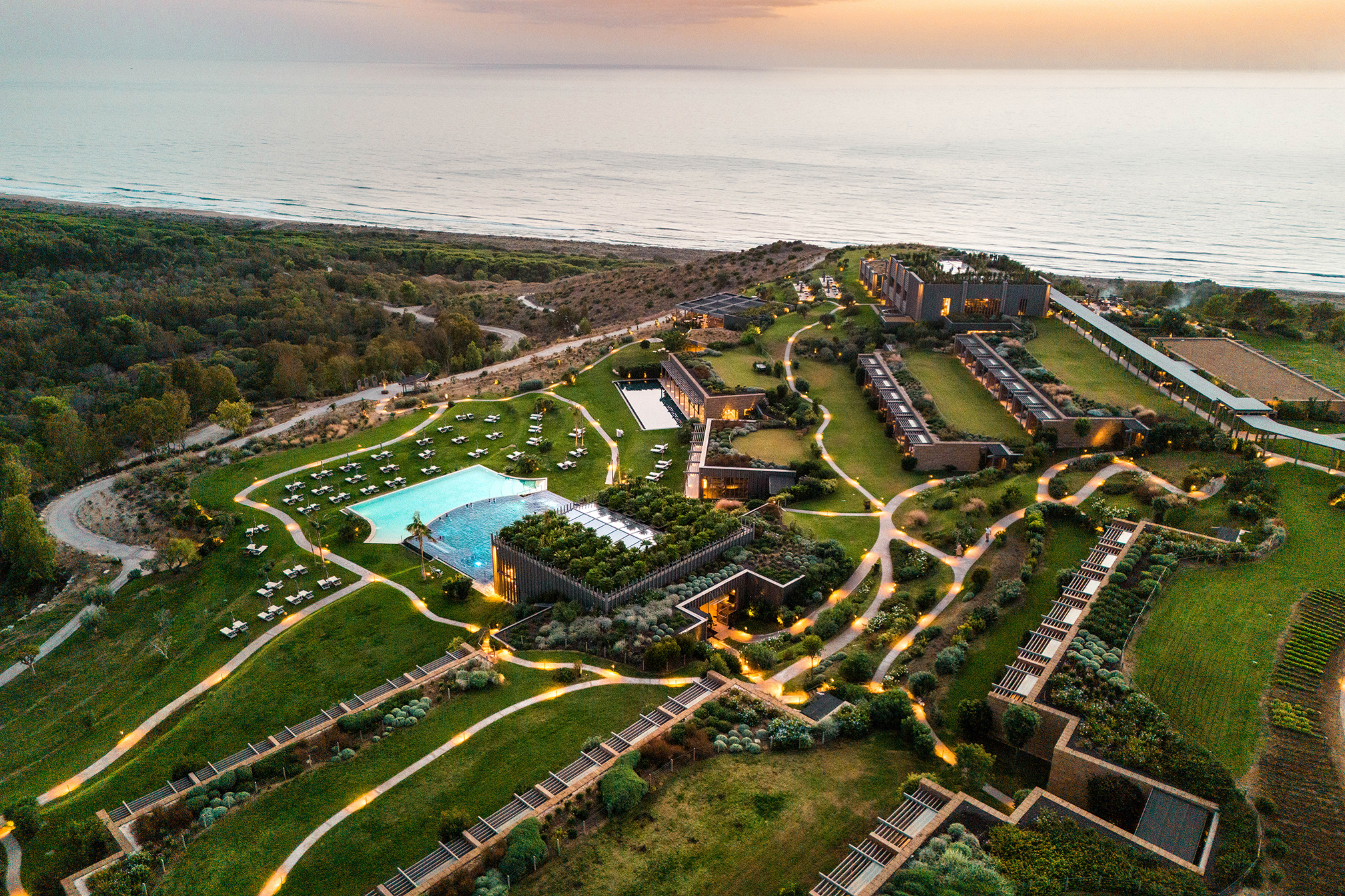 Aerial of entire resort with roads weaving between two buildings lit up at dusk