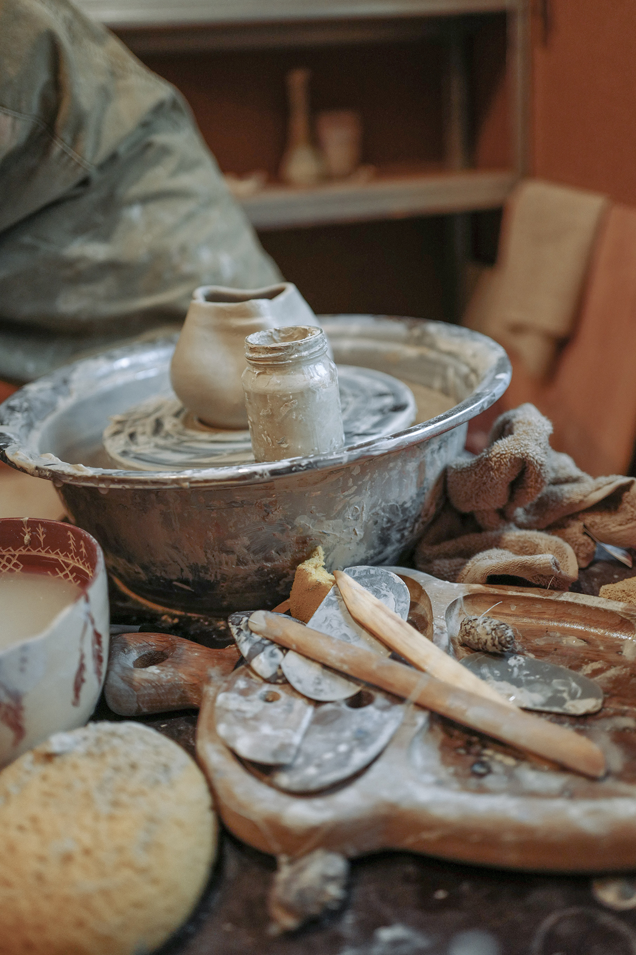 A potter's wheel surrounded by pottery and equipment
