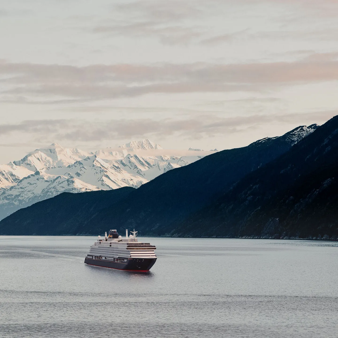 Cruise, Explora Journeys, Explora III cruise ship sailing on cold waters with dark and snowy mountains in the background