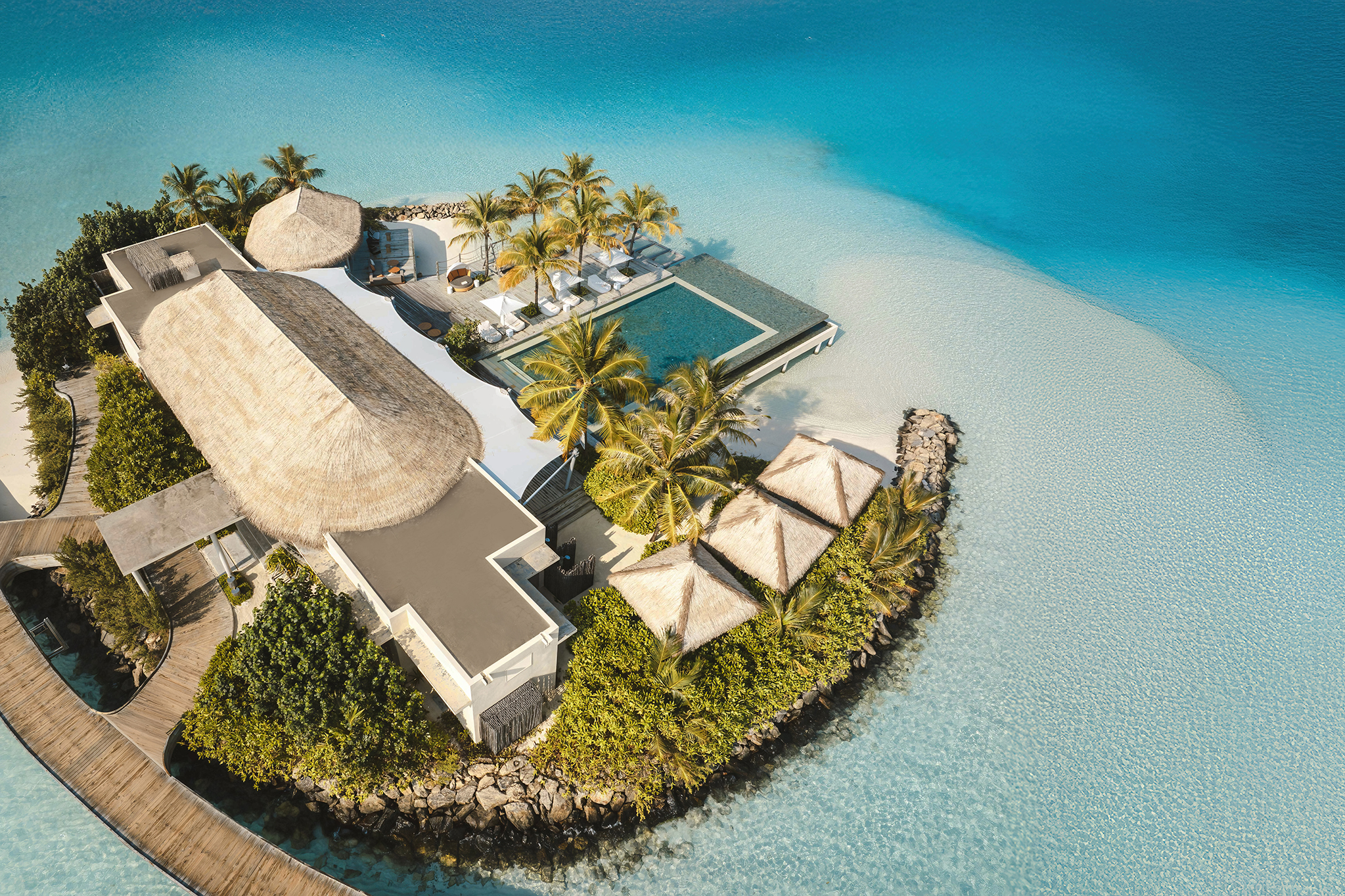 Aerial view of The Retreat and its infinity pool at InterContinental Maldives surrounded by turquoise waters.
