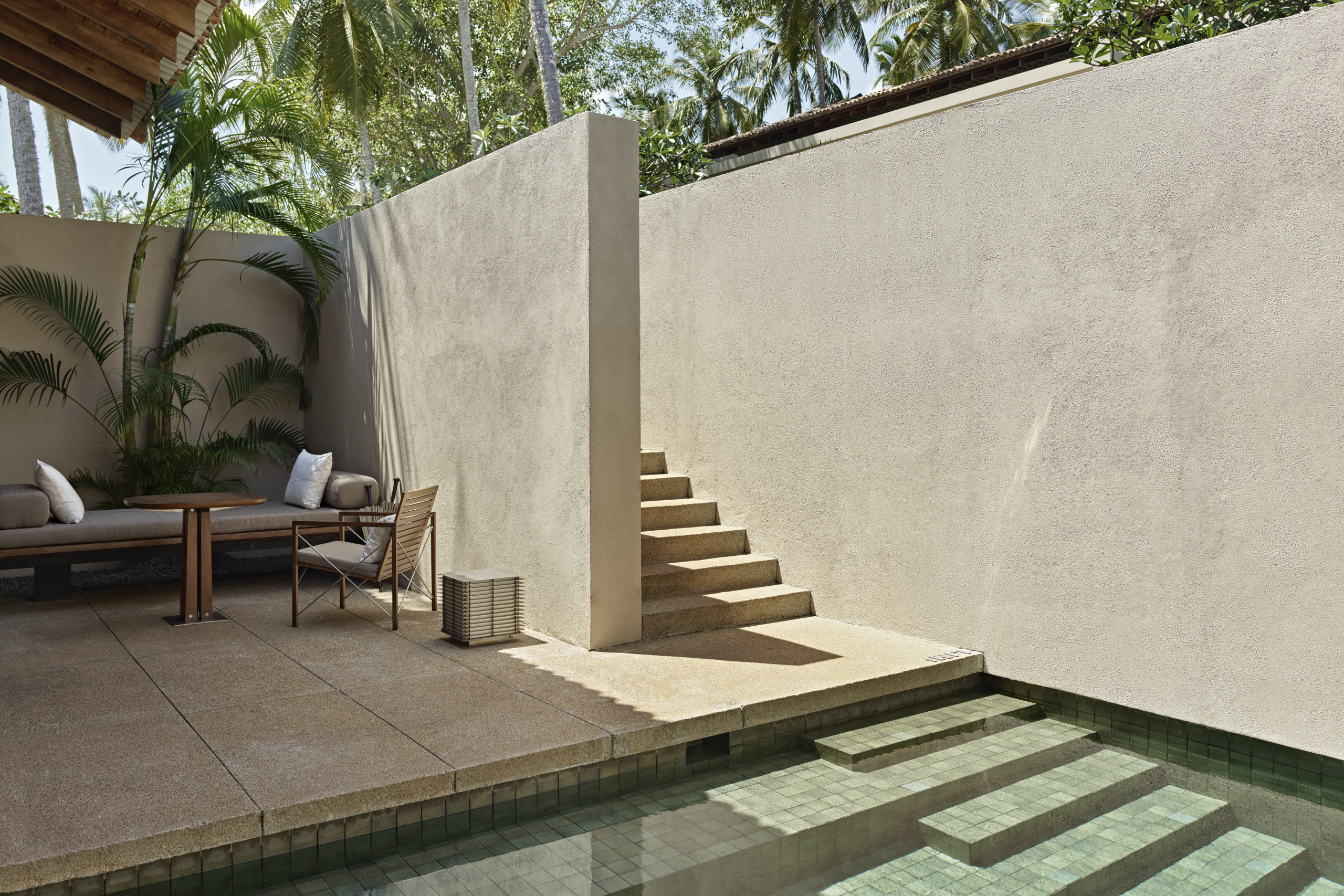 Private garden with deck furniture and stone steps leading down the a pool
