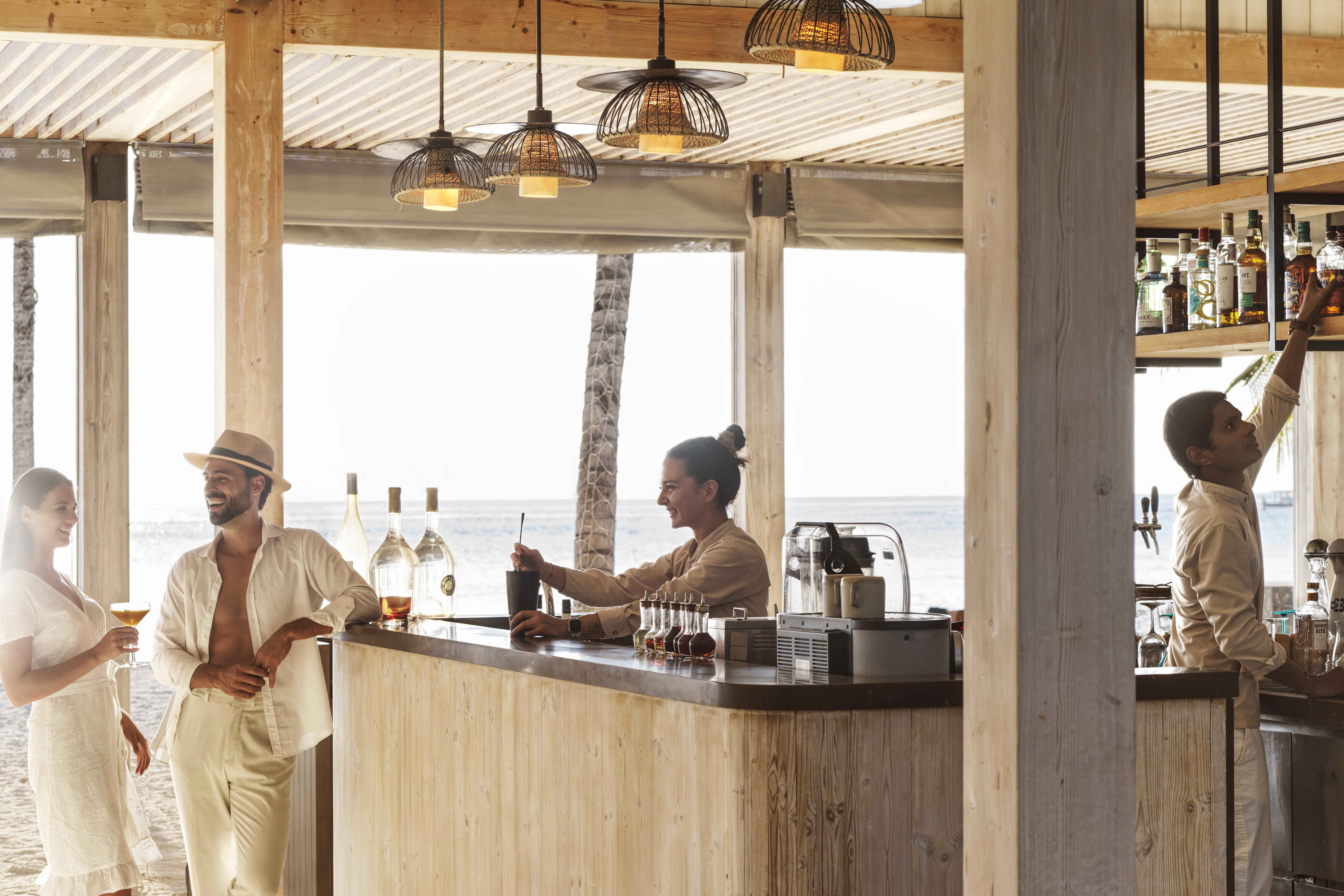 A couple and two bartenders at the Beach Shack Bar mixing cocktails