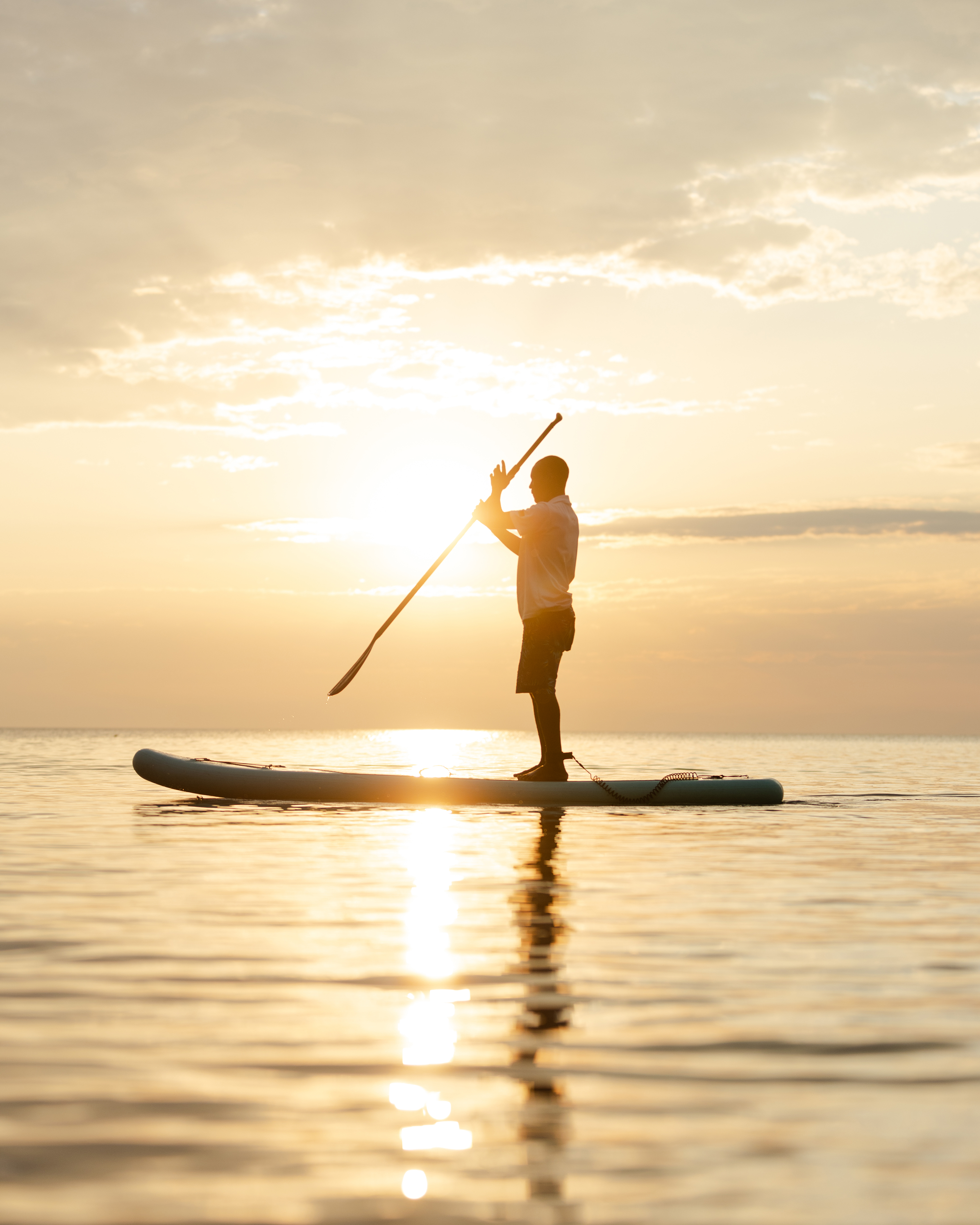 Person paddleboarding at Kaya Mawa on calm water during a golden sunset.