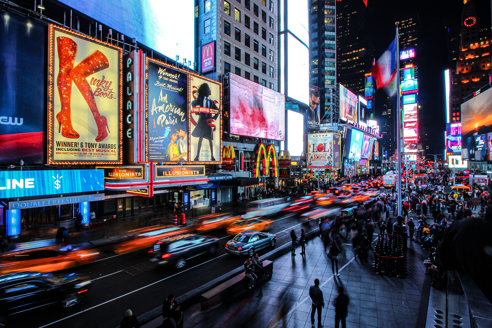 Blurred cars and people walking under the led signs at Times Square
